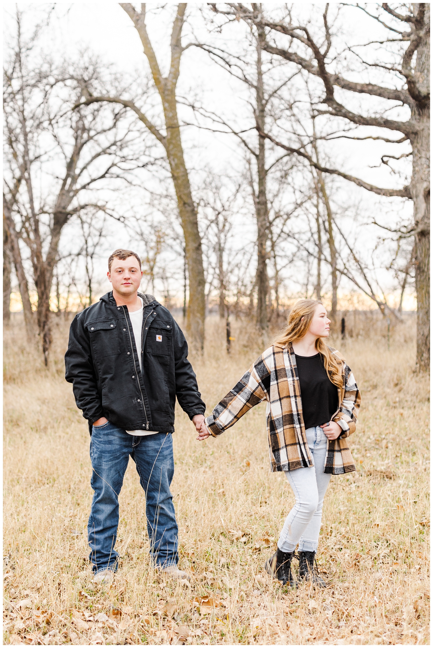 Travis and Abi hold hands in a grassy filed in Iowa in the middle of winter | CB Studio
