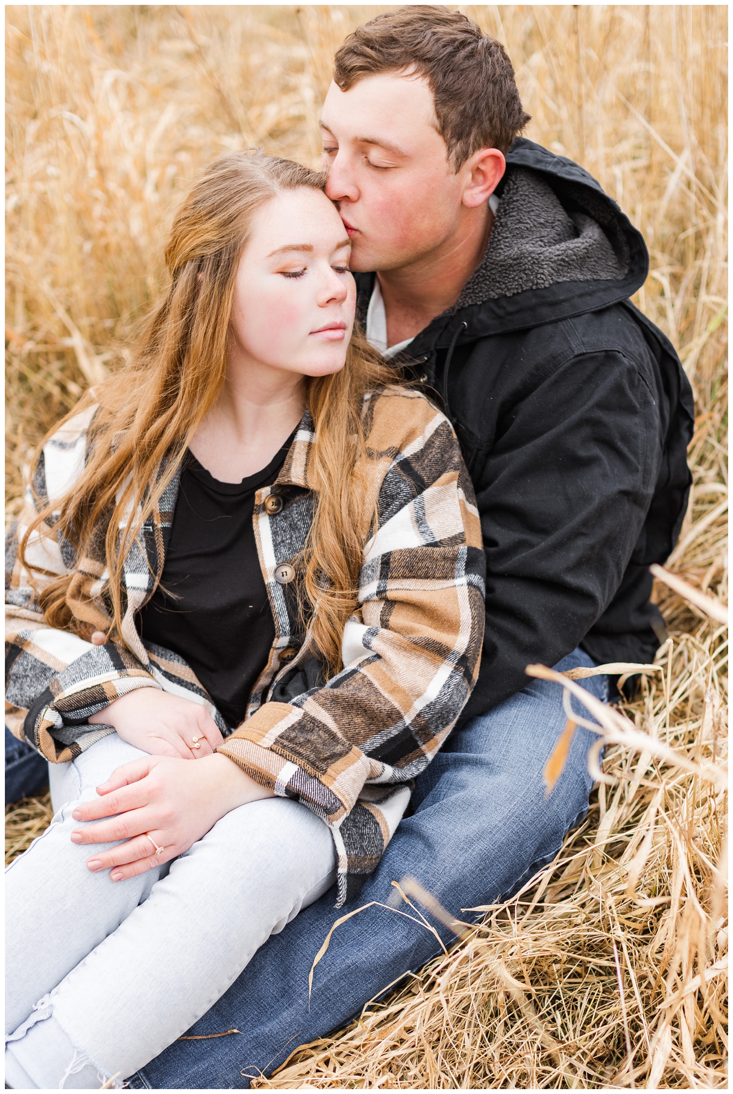 Travis snuggles his fiance Abi while sitting in a grassy filed in Iowa in the middle of winter | CB Studio