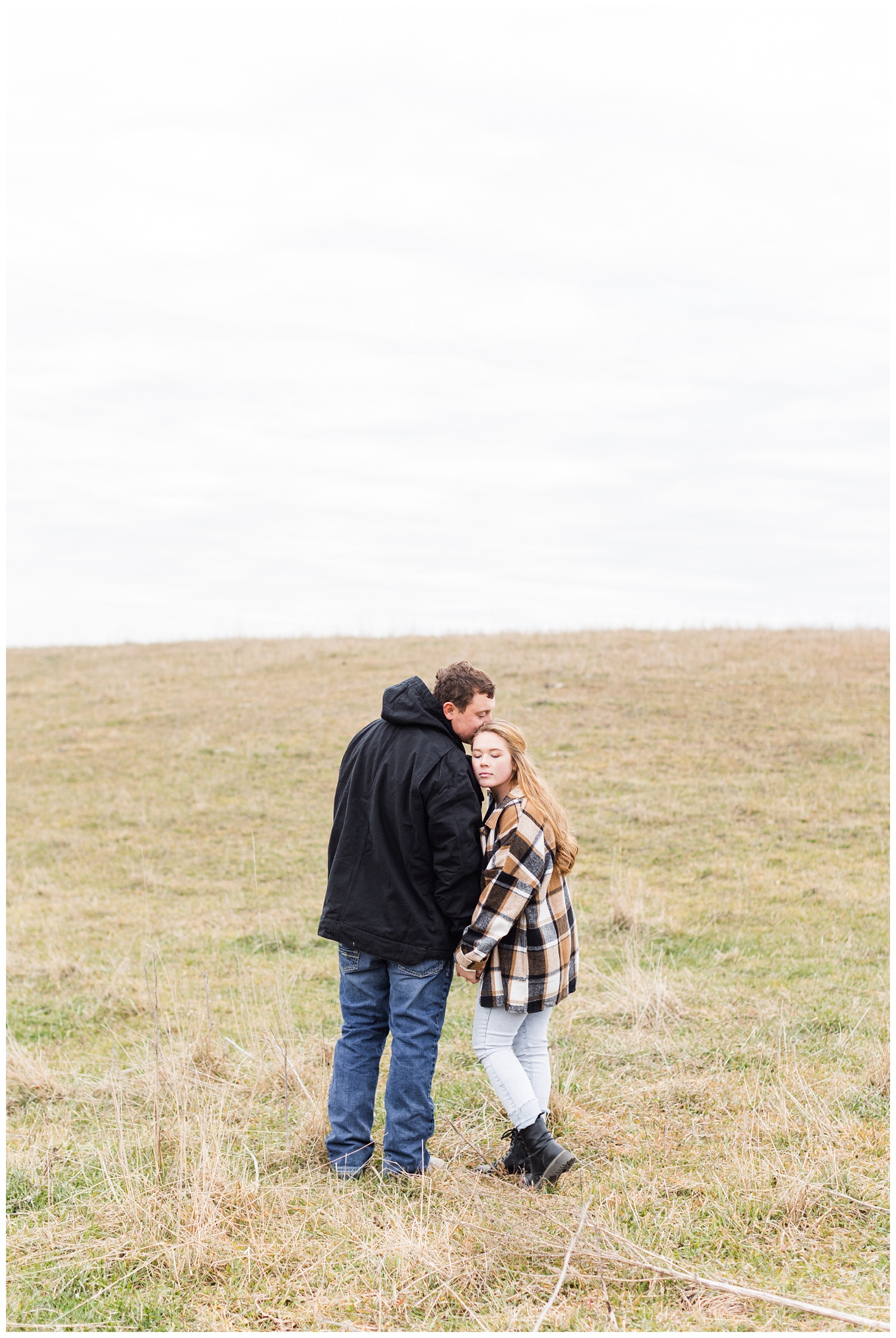 Abi leans on Travis's shoulder on a grassy hill in Iowa in the middle of winter | CB Studio