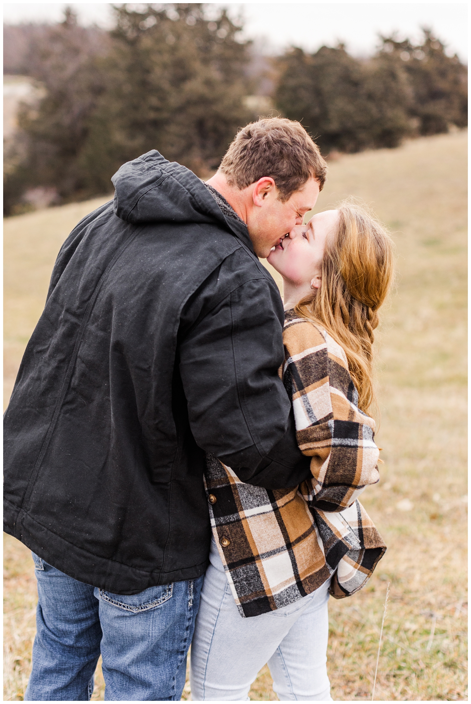 Travis and Abi share a kiss in a grassy filed in Iowa in the middle of winter | CB Studio