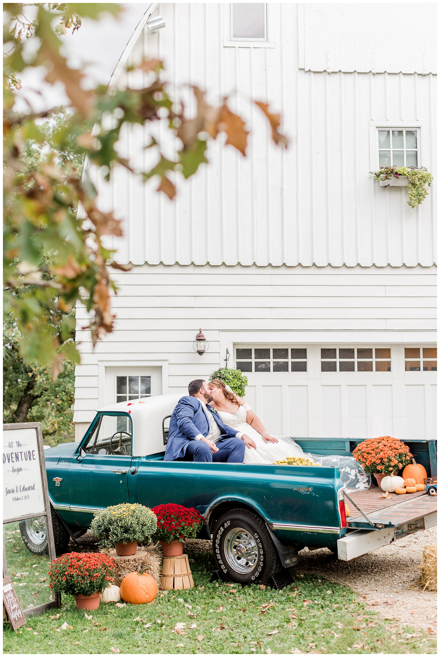 Bride and groom kiss in the back of an old blue Chevy truck in front of a white barn | CB Studio