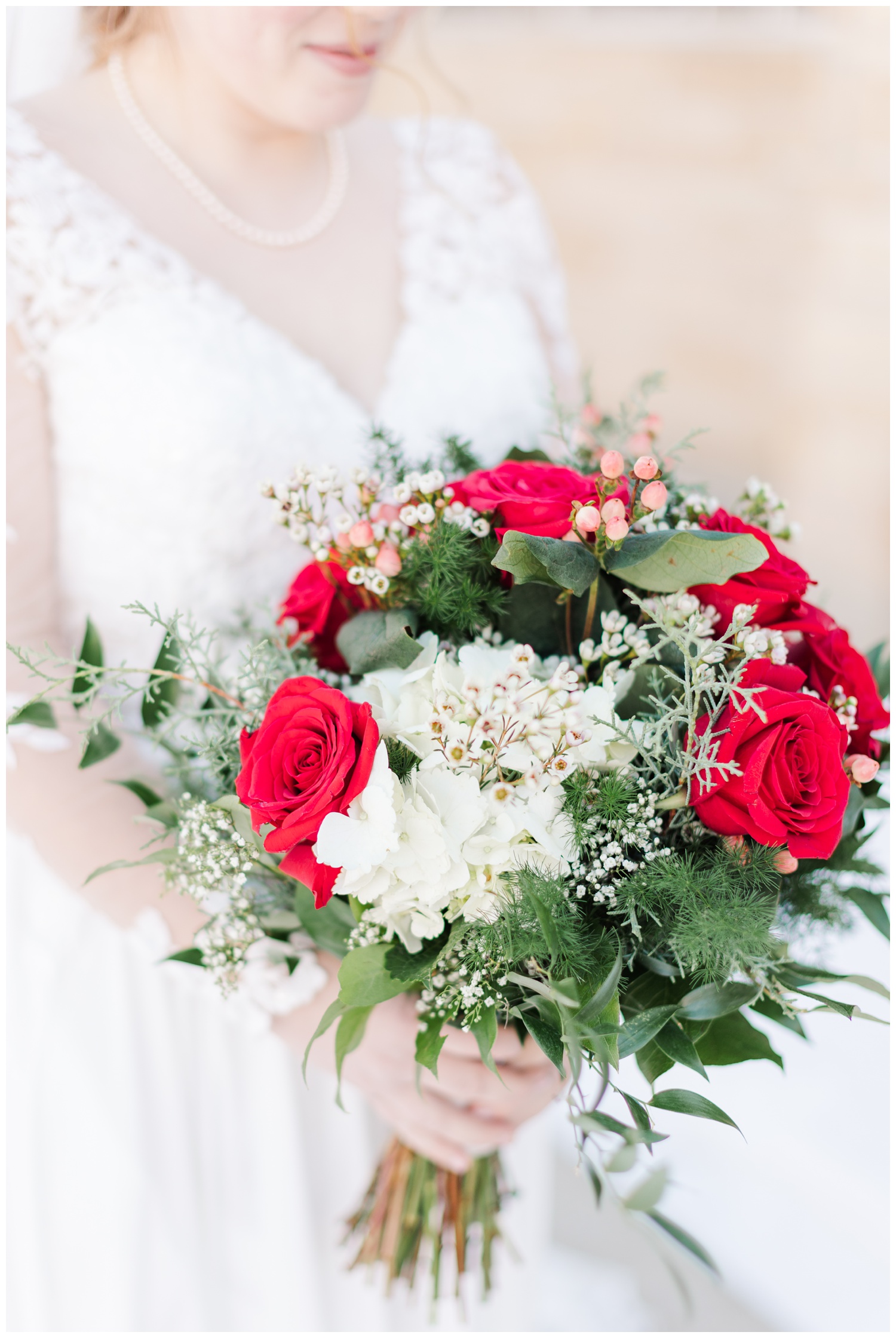 Winter wedding bridal bouquet featuring red roses, white hydrangeas, holly berries, evergreen and baby's breath | CB Studio
