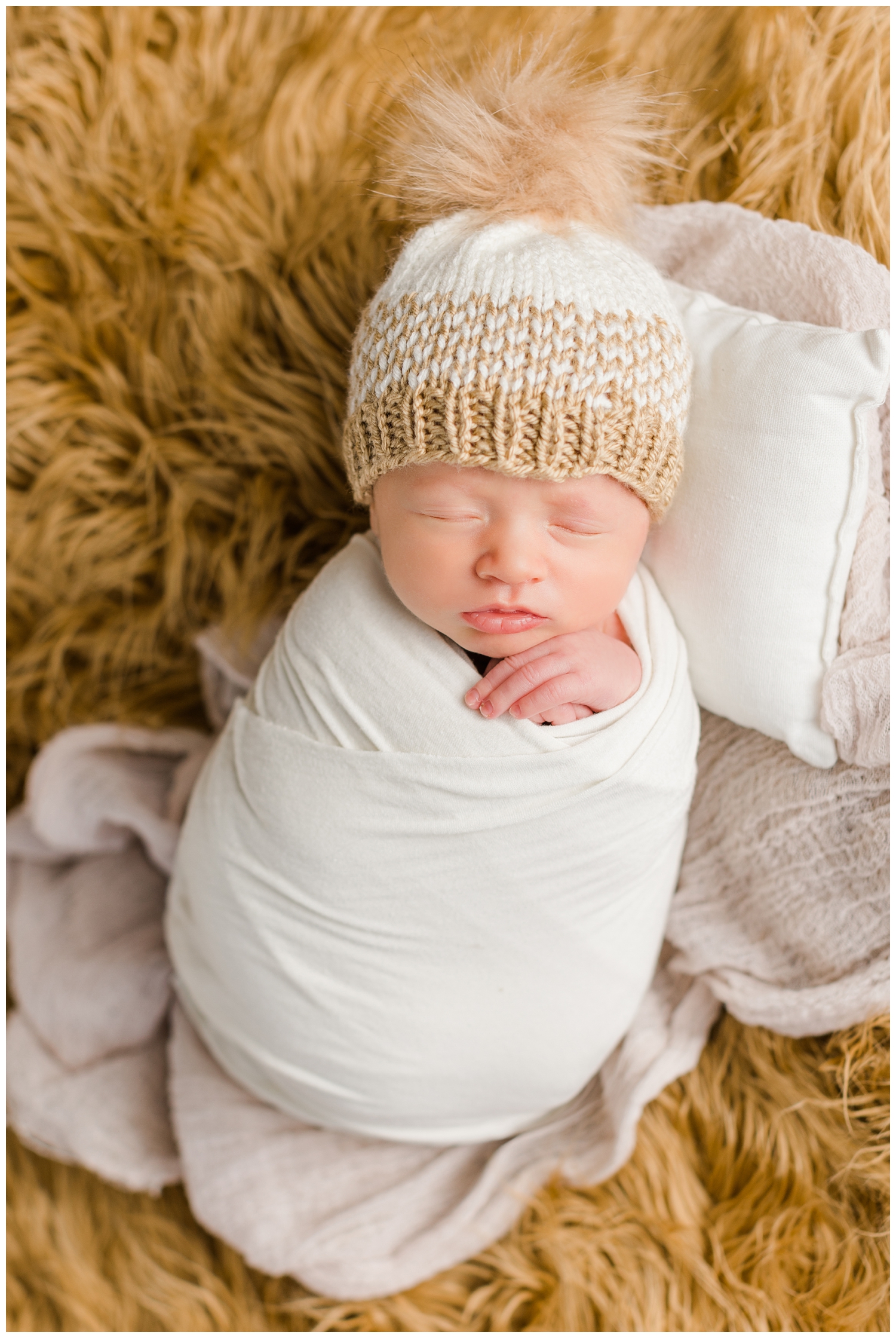 Baby Hudsyn wrapped in white and wearing a knit beanie and nestled on a camel colored flotaki | CB Studio