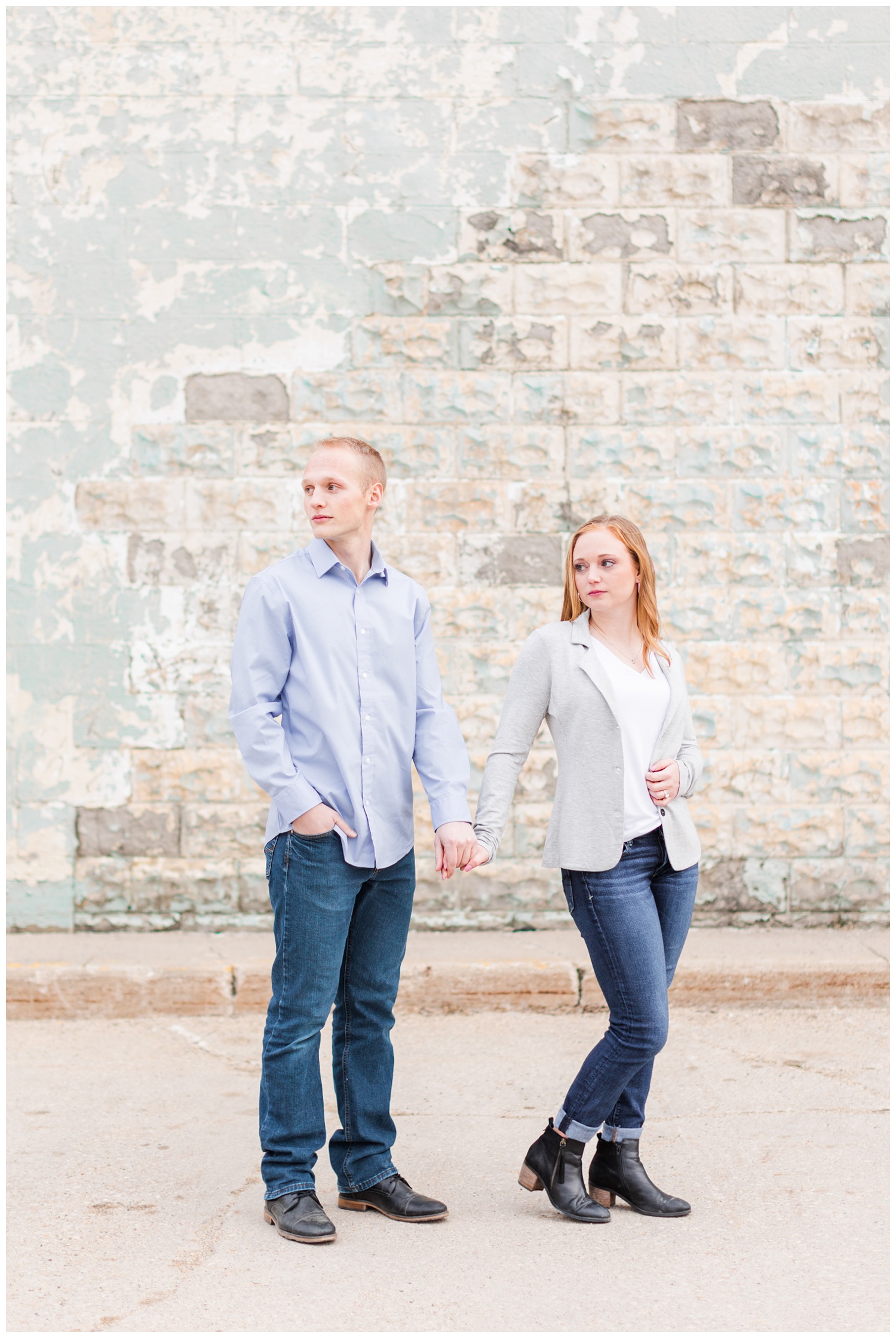 Brenna and Jacob stand holding hands in front of a rustic stone building colored mint and cream | CB Studio