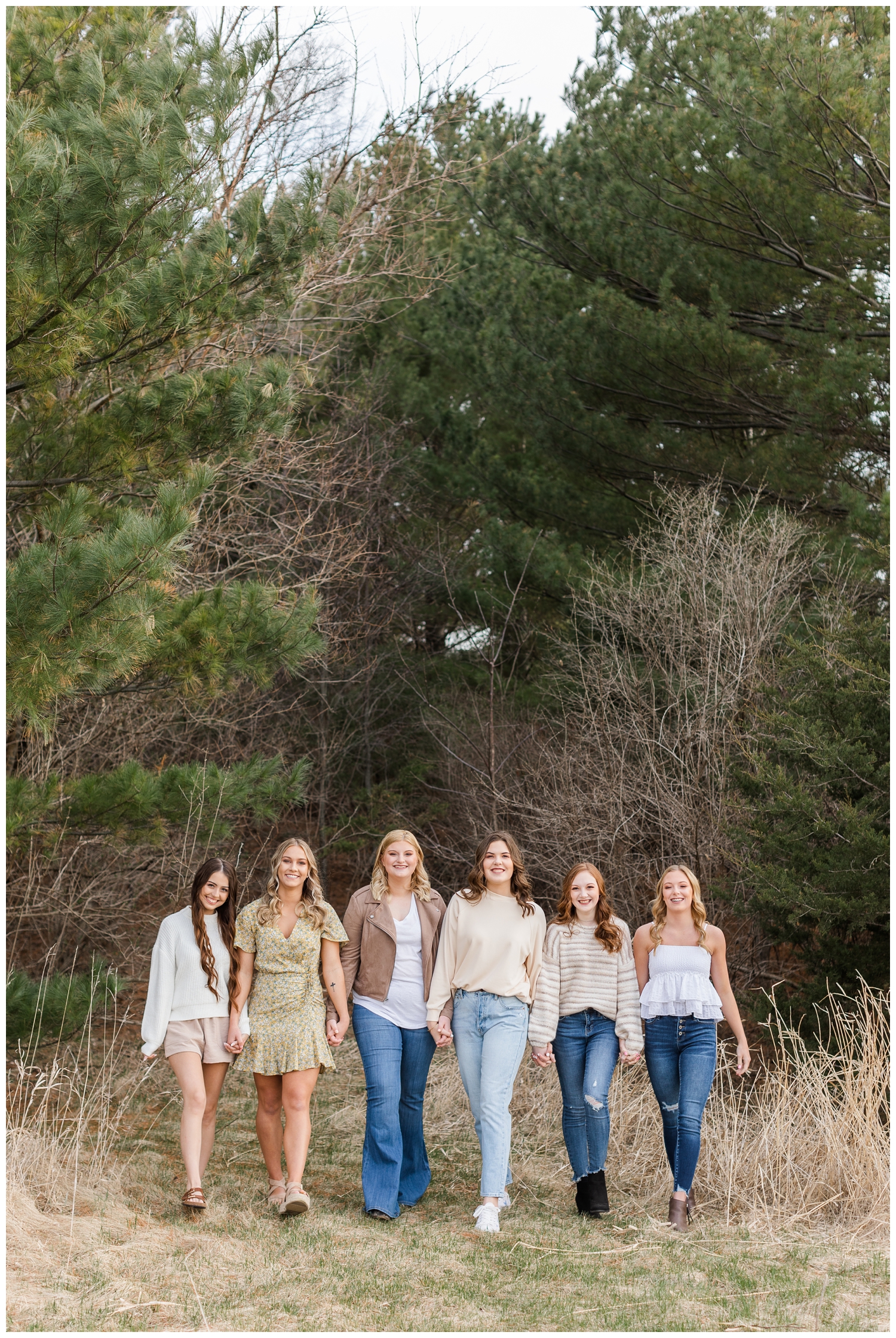 2023 senior spokesmodels hold hands while walking in a grassy field | CB Studio