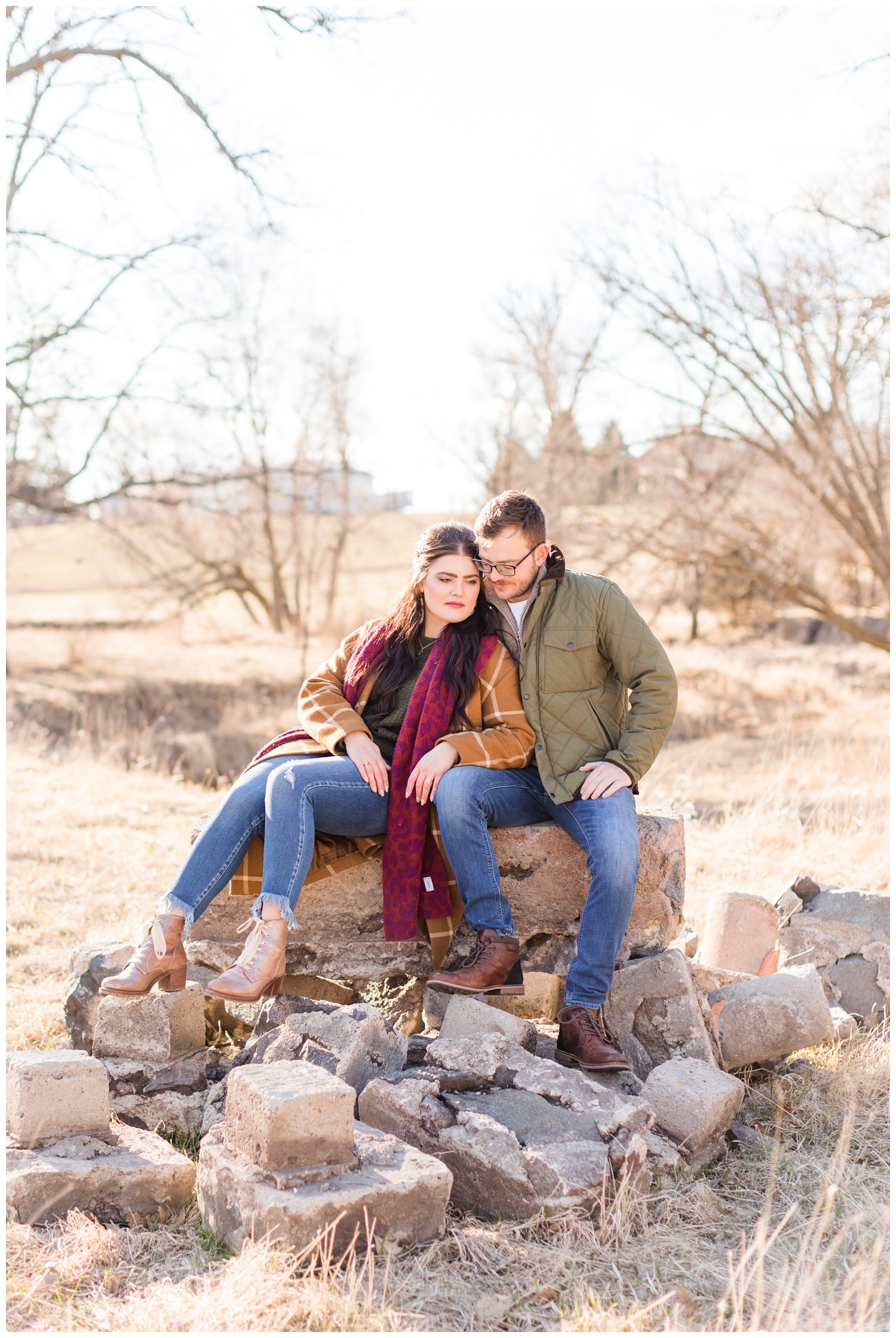 Rachel and Mitch snuggle together on a pile of stones during their engagement session | CB Studio