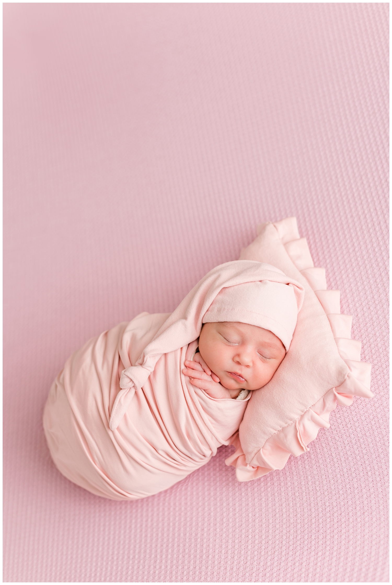 Baby Hazel all wrapped in pink and wearing a night cap | CB Studio