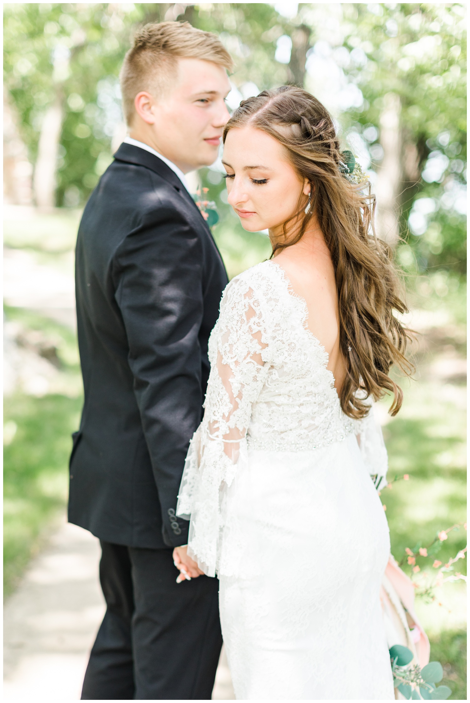 Thad looks back at his bride as they walk along a path at Gull Point State Park | CB Studio