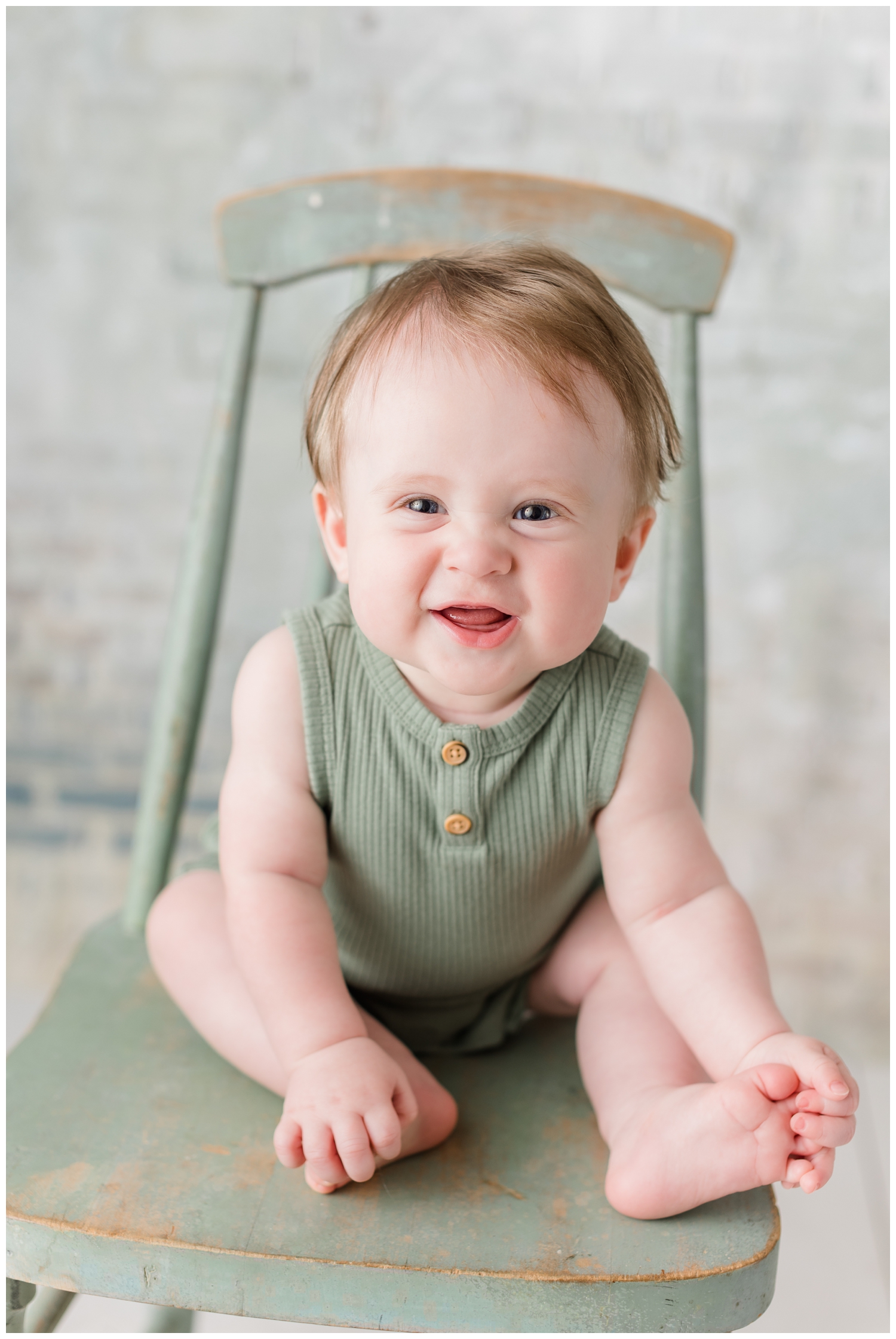 Baby Brooks scrunches his nose while sitting on a vintage green chair | CB Studio