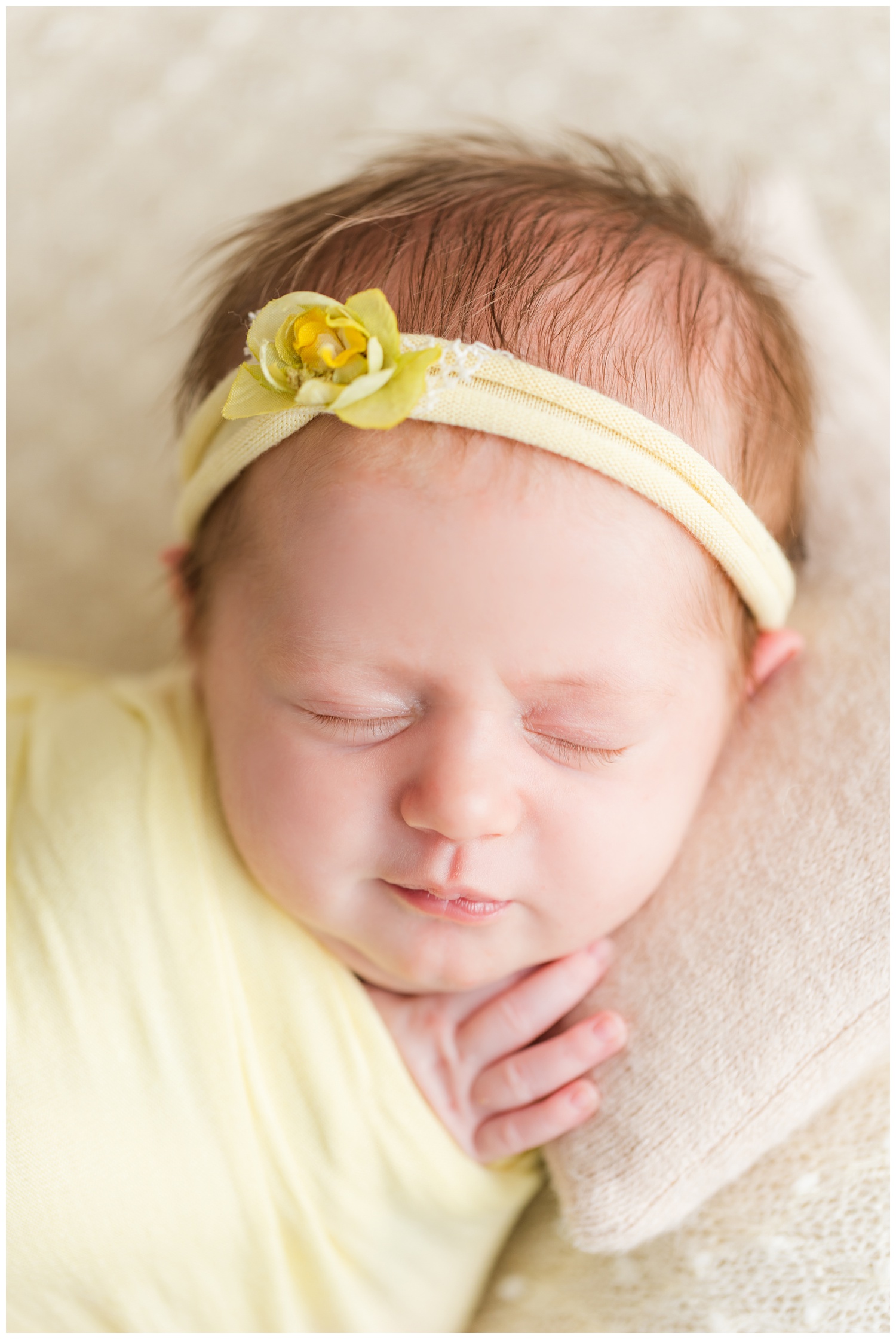 Baby Mackenzie wrapped in yellow scrunches her nose as she sleeps on a cream knit blanket | CB Studio