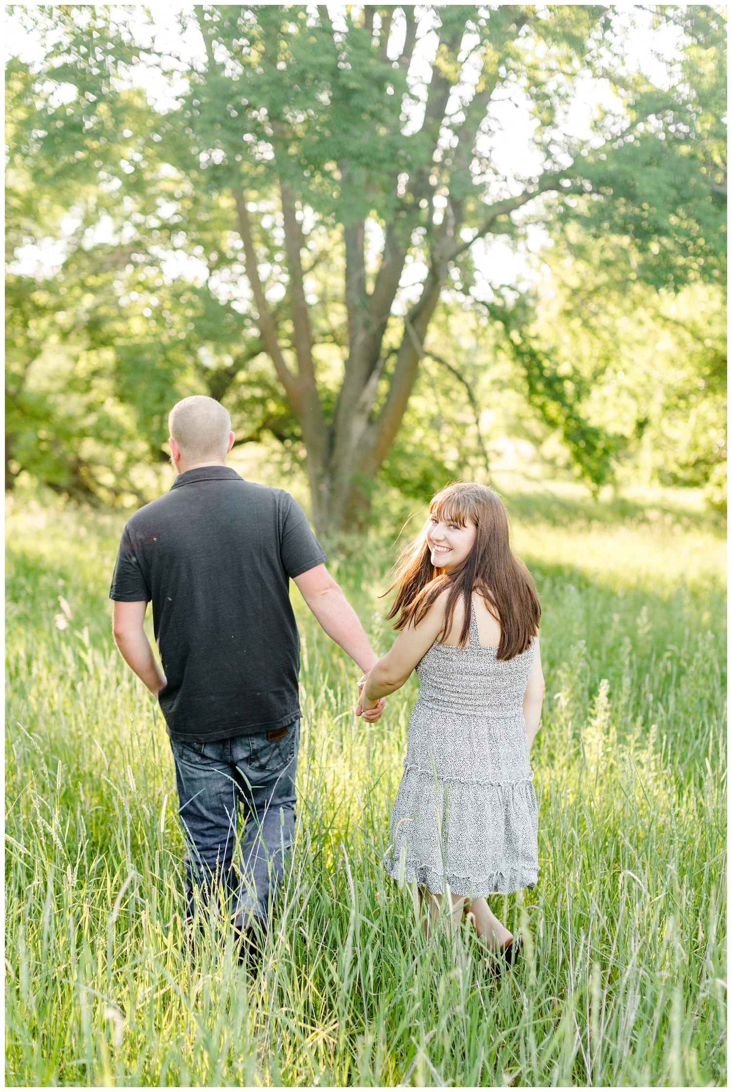 Madeline smiles back as she and Jeremiah walk away in a grassy pasture in Iowa | CB Studio