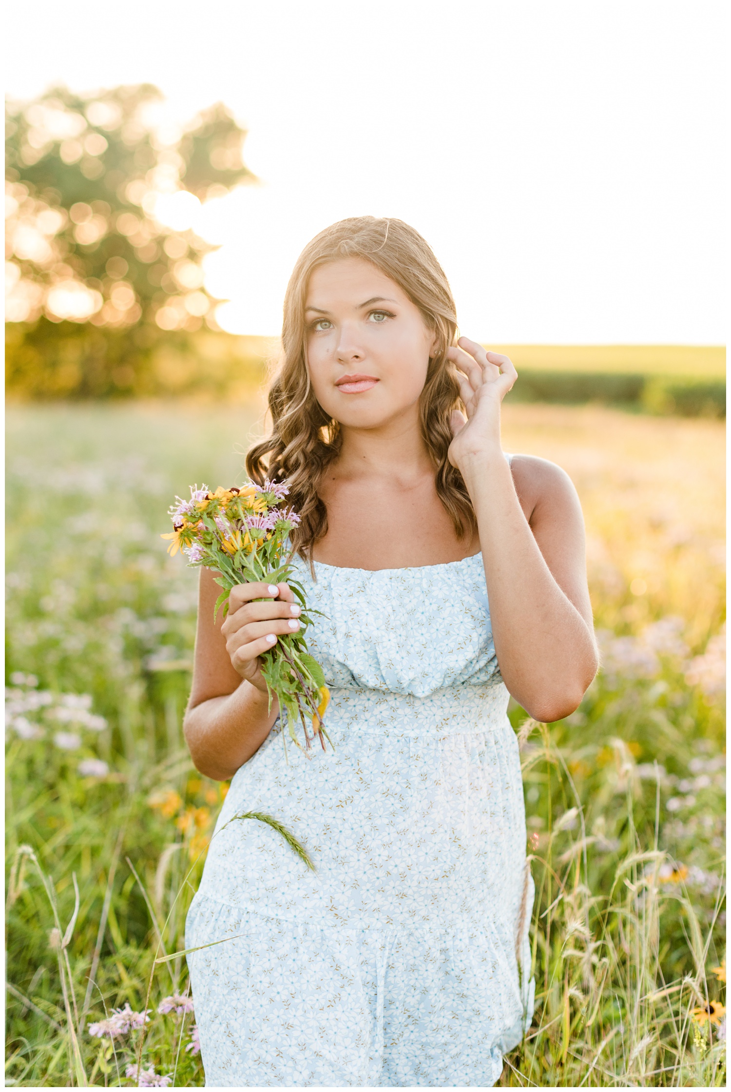 Analia walks gracefully as she tucks her hair behind her ear in the middle of a wildflower field in Iowa | CB Studio