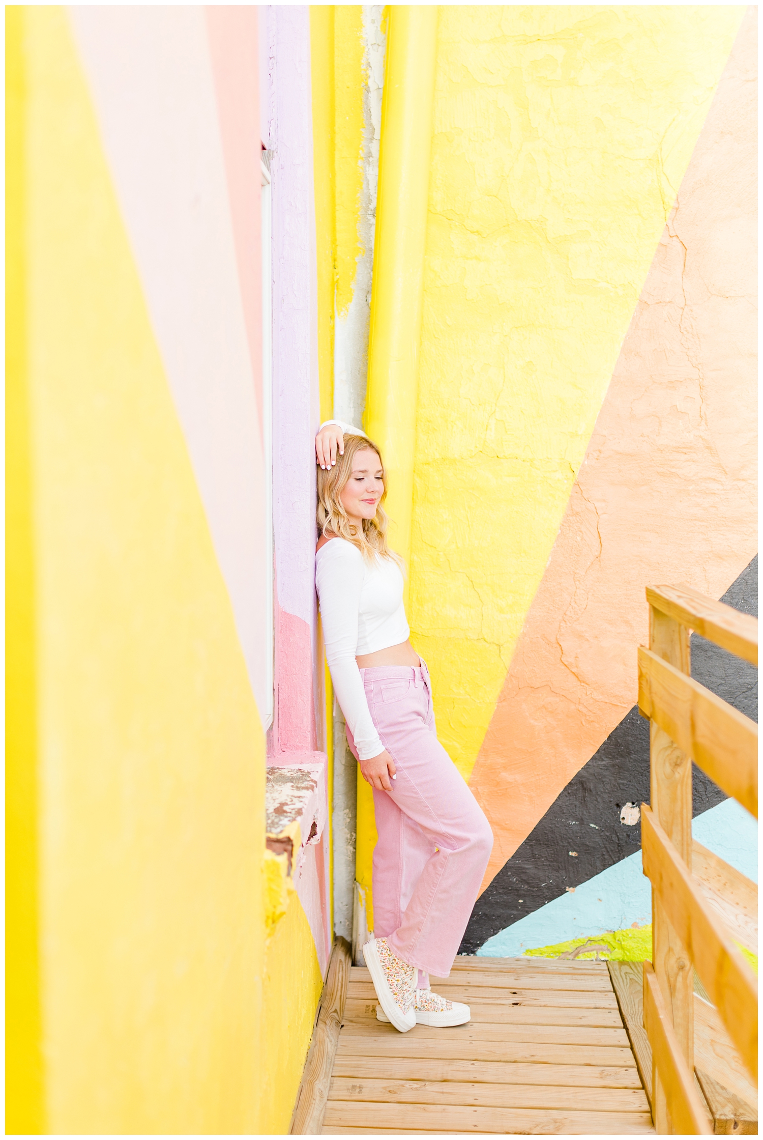 Cassie leans on a build featuring a colorful mural in downtown Algona, IA | CB Studio