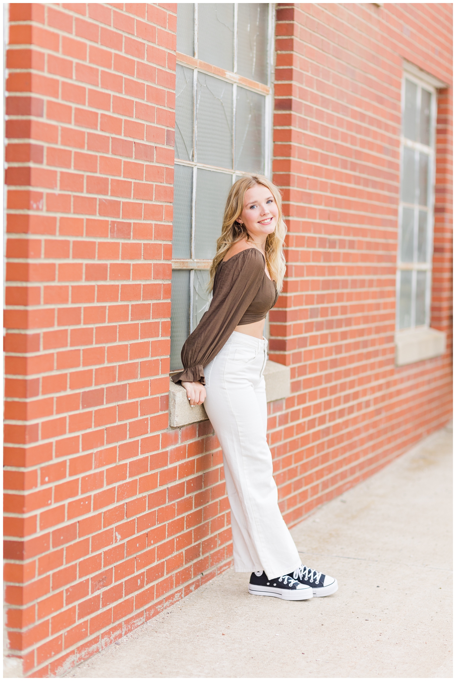 Cassie leans on an old brick building in downtown Algona, IA | CB Studio
