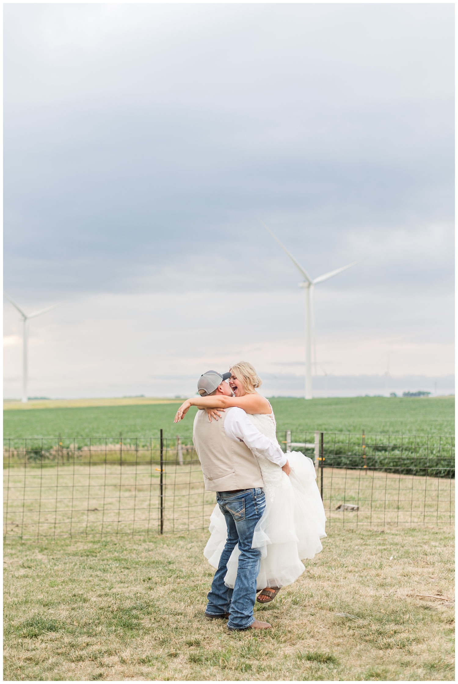 Braden picks up his bride on an Iowa farm with rain clouds and windmills in the background | CB Studio
