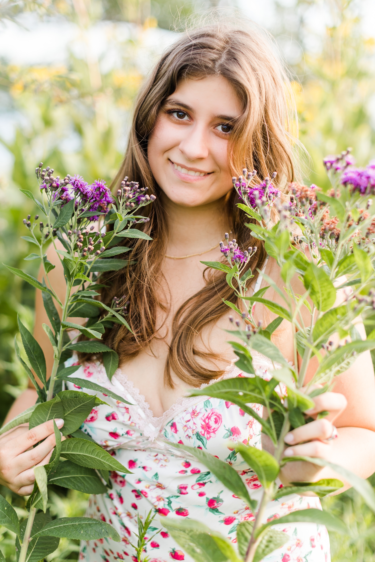 Caitlin smiles in a field of purple wildflowers wearing a strawberry slip dress from Cultivate Boutique | CB Studio