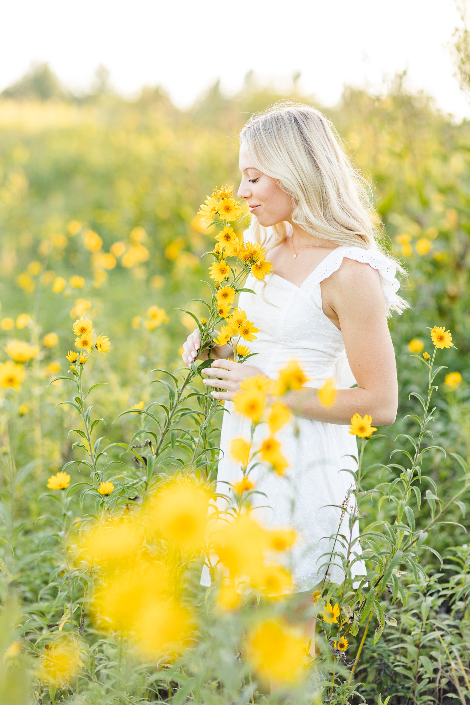Shelby gentle smells beautiful yellow flowers in a field of wildflowers at Water's Edge Nature Center | CB Studio