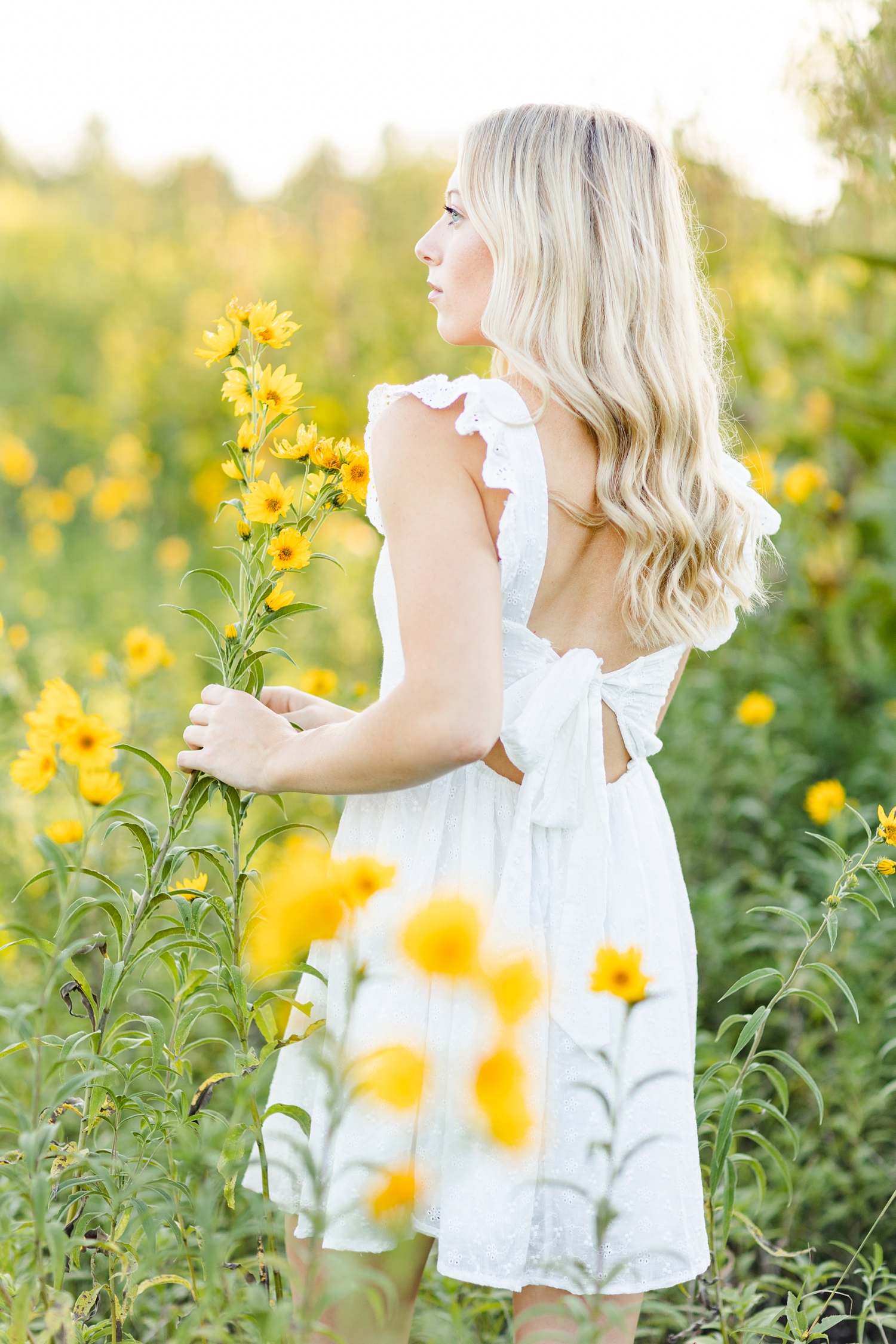 Shelby looks off in the distance in a field of yellow wildflowers at Water's Edge Nature Center | CB Studio