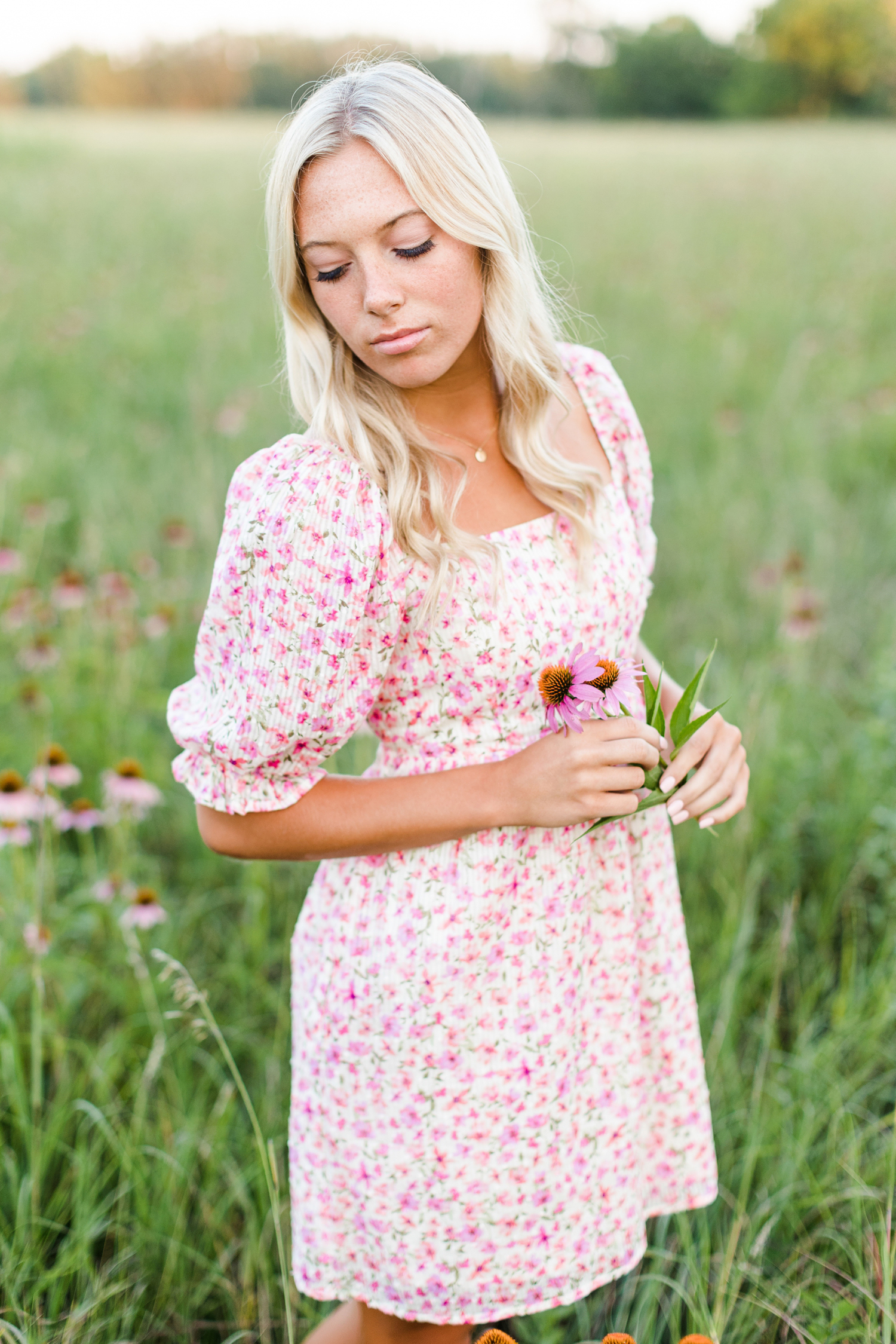 Shelby poses in a pink wildflower field wearing a pink floral dress | CB Studio