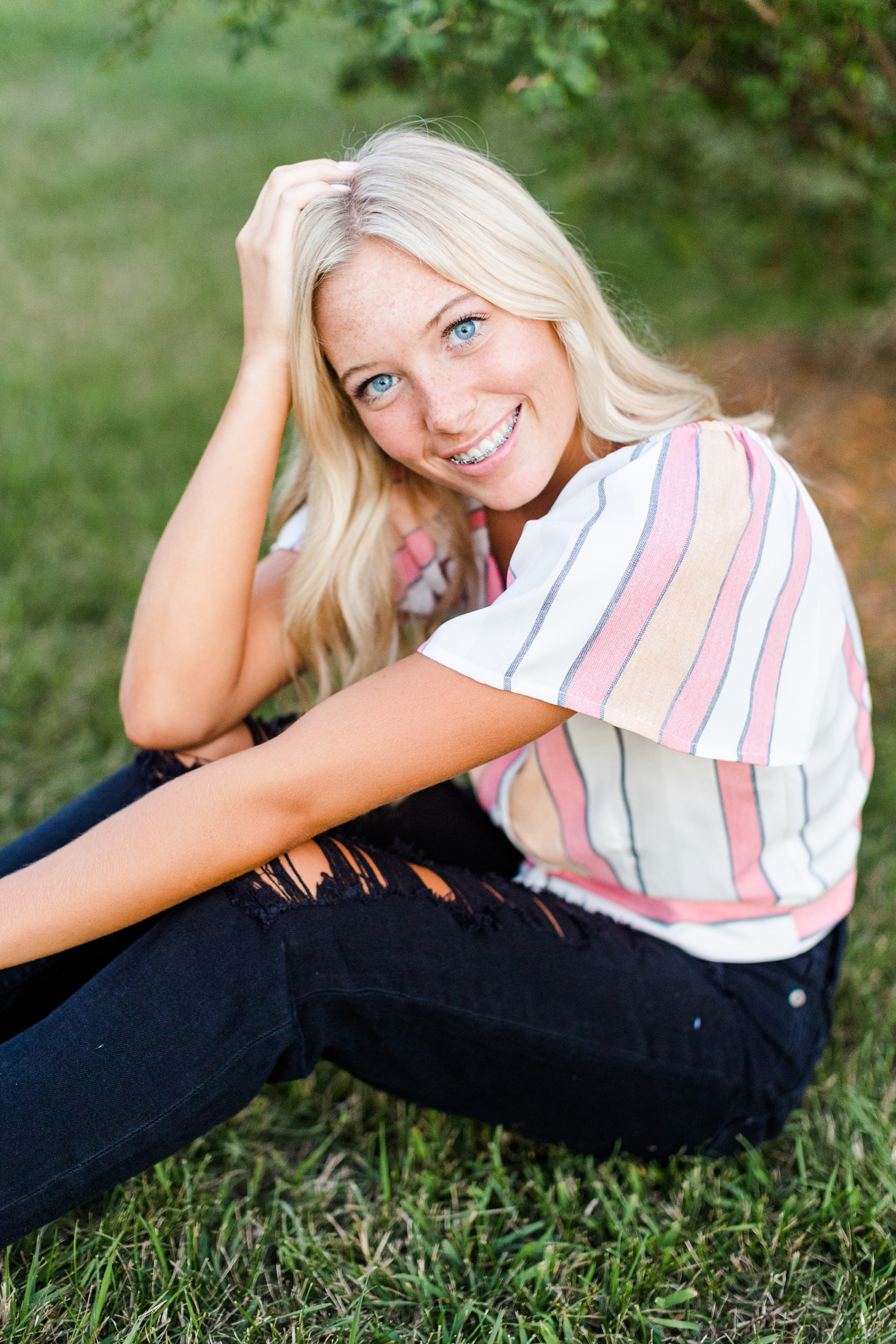 Shelby sits in the grass and smiles in Armstrong, IA | CB Studio