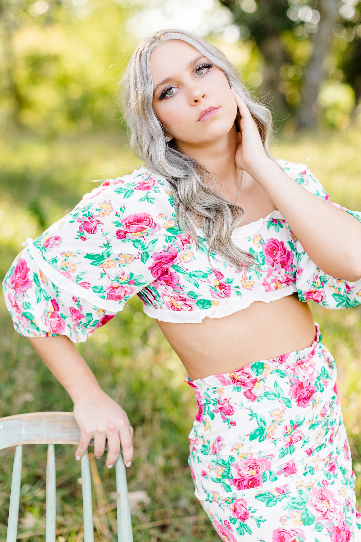 Shelby leans against a vintage green chair wearing a floral matching mini skirt set | CB Studio