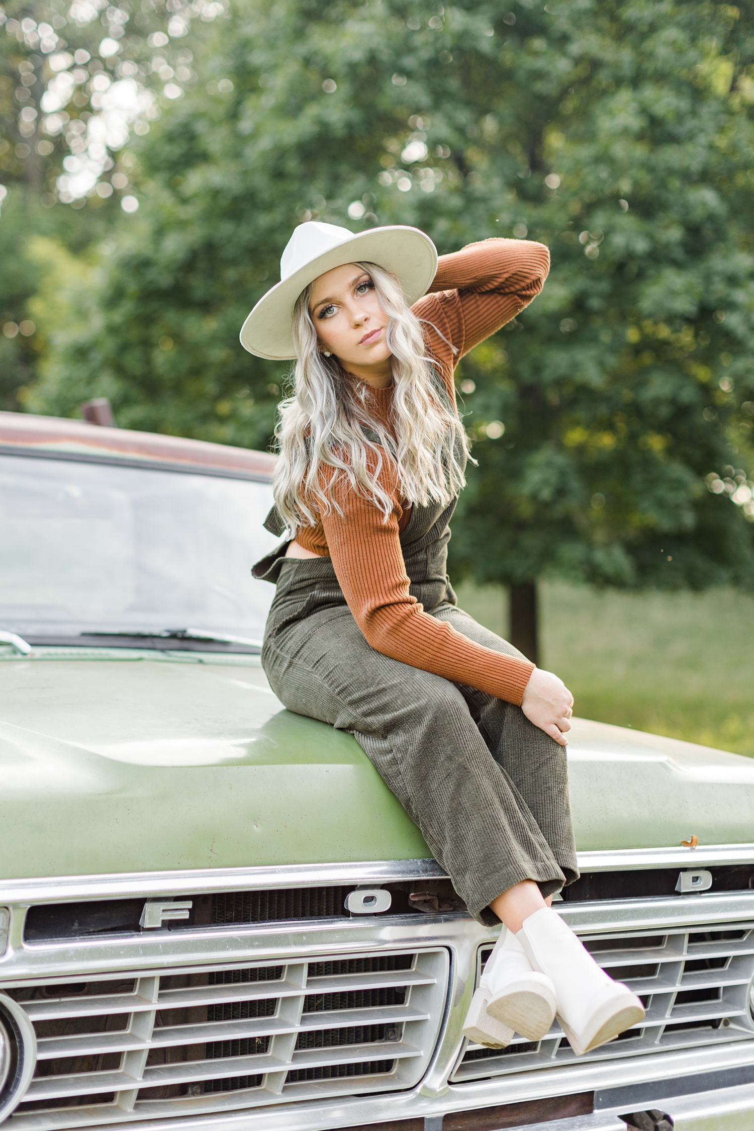 Shelby sits on the hood of a green 72 Ford truck in the middle of a grassy pasture | CB Studio