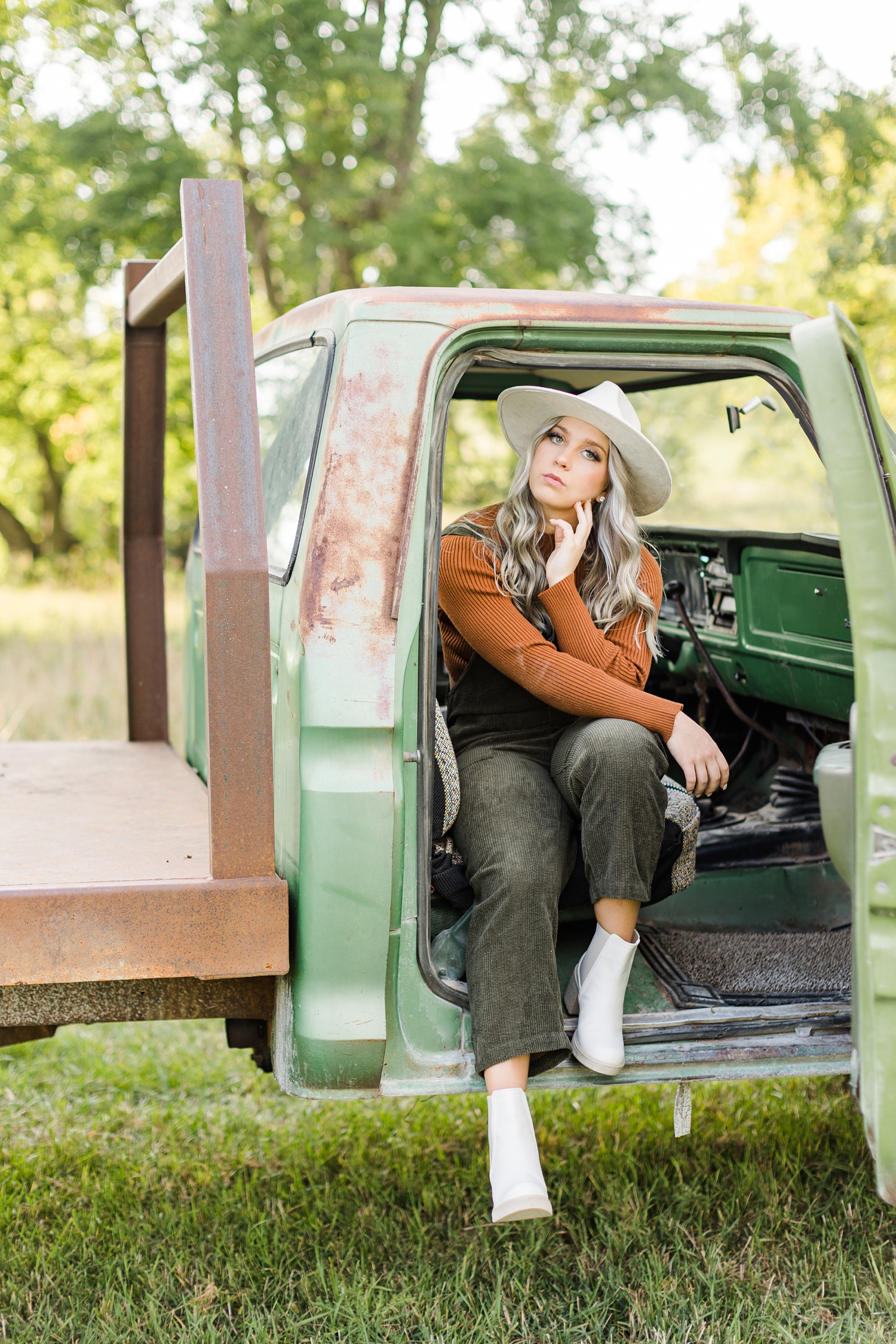 Shelby sits inside of a green 72 Ford truck in the middle of a grassy pasture | CB Studio