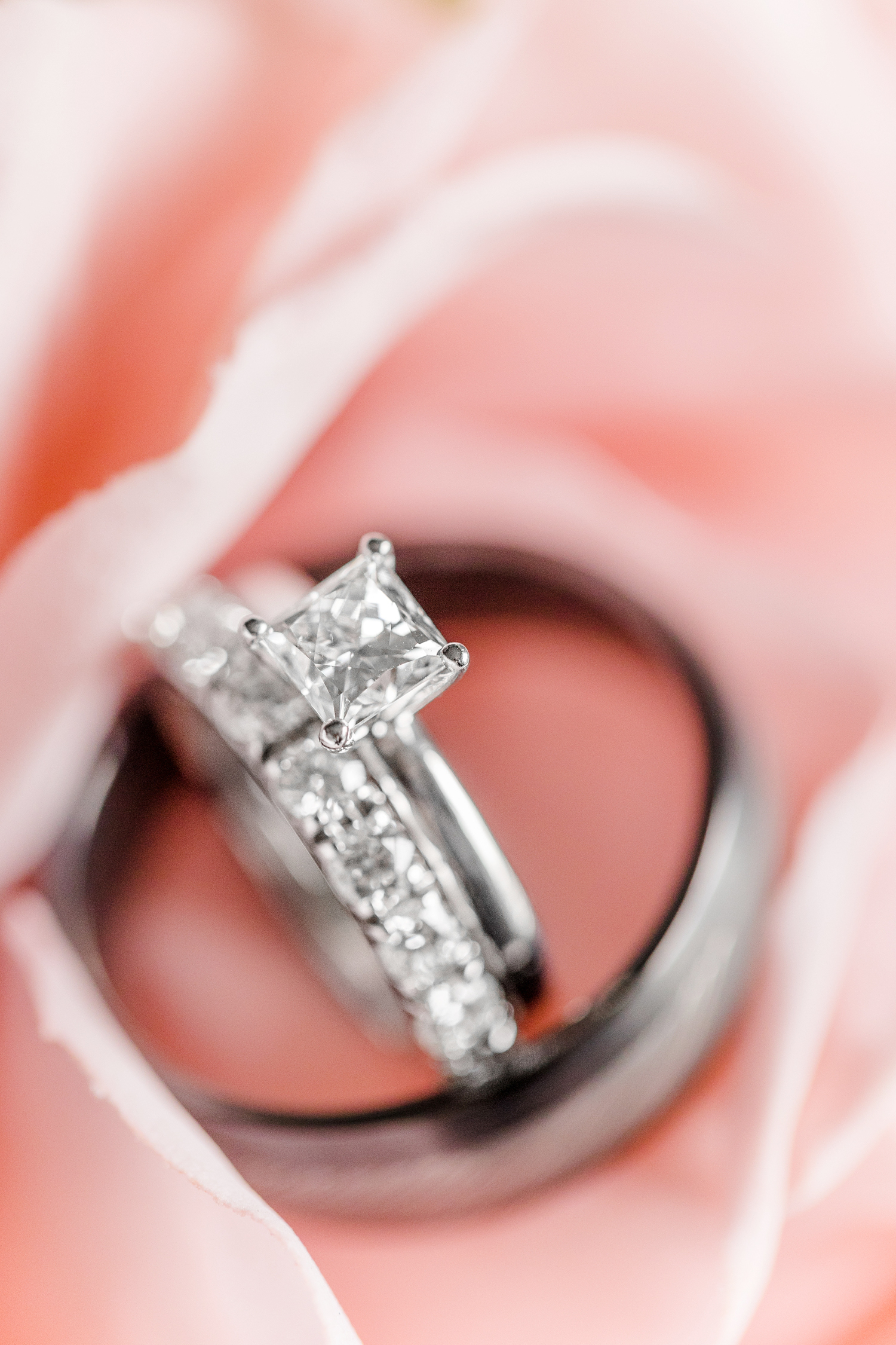 Princess cut diamond with eternity wedding band nestled on a soft pink rose | CB Studio