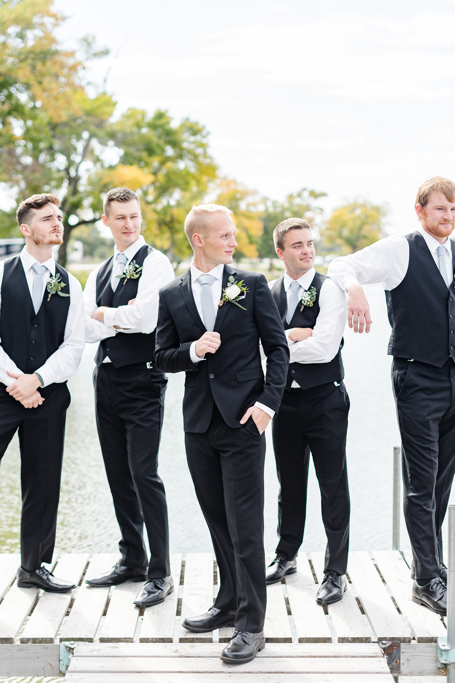 Jacob and his groomsmen stand on a dock looking out at Five Island Lake | CB Studio