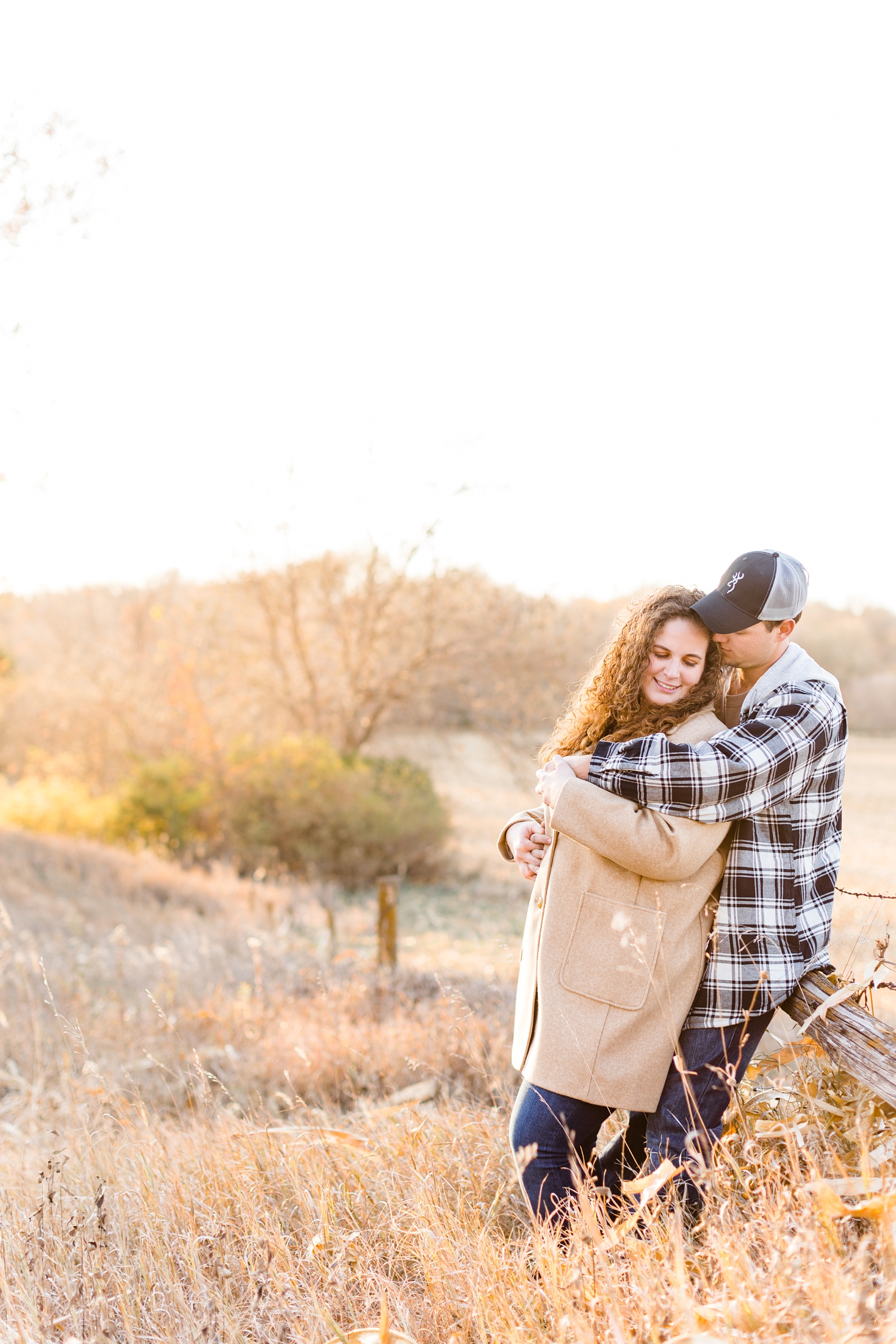 Dakota hugs Holly as they lean against a wooden fence along an Iowa pasture | CB Studio