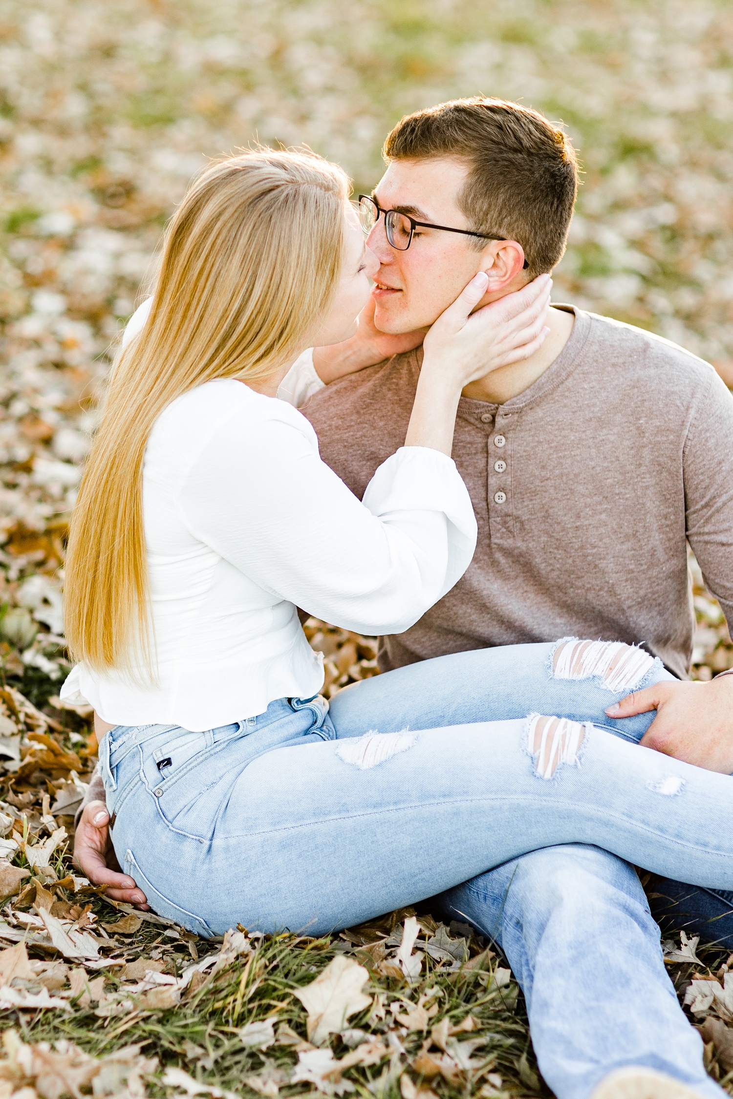 Alli slowly pulls Quinton in for a kiss while sitting in a grassy pasture full of leaves  | CB Studio