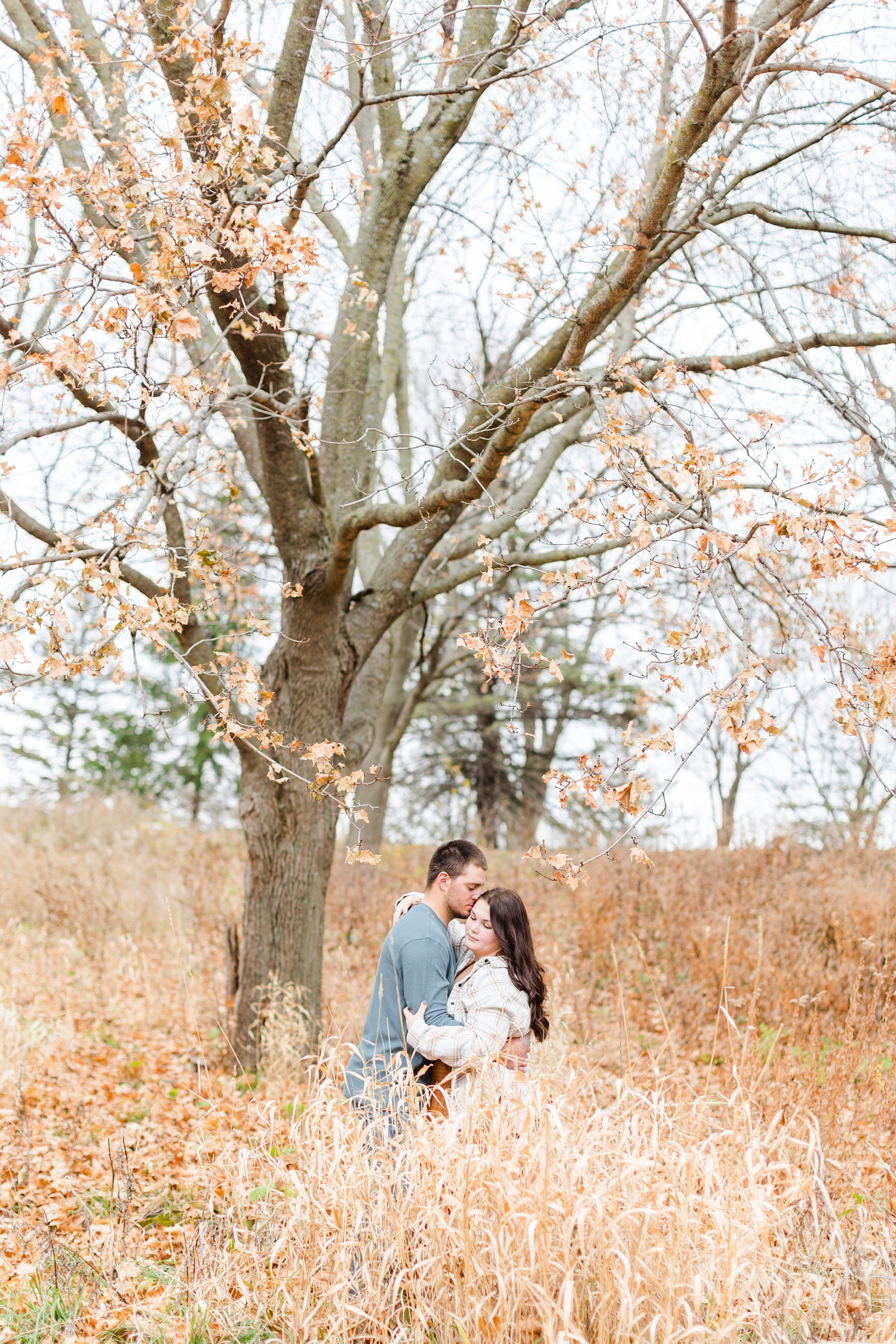 Mary and Austin embrace in the fall leaves at Kennedy Park in Fort Dodge, IA | CB Studio