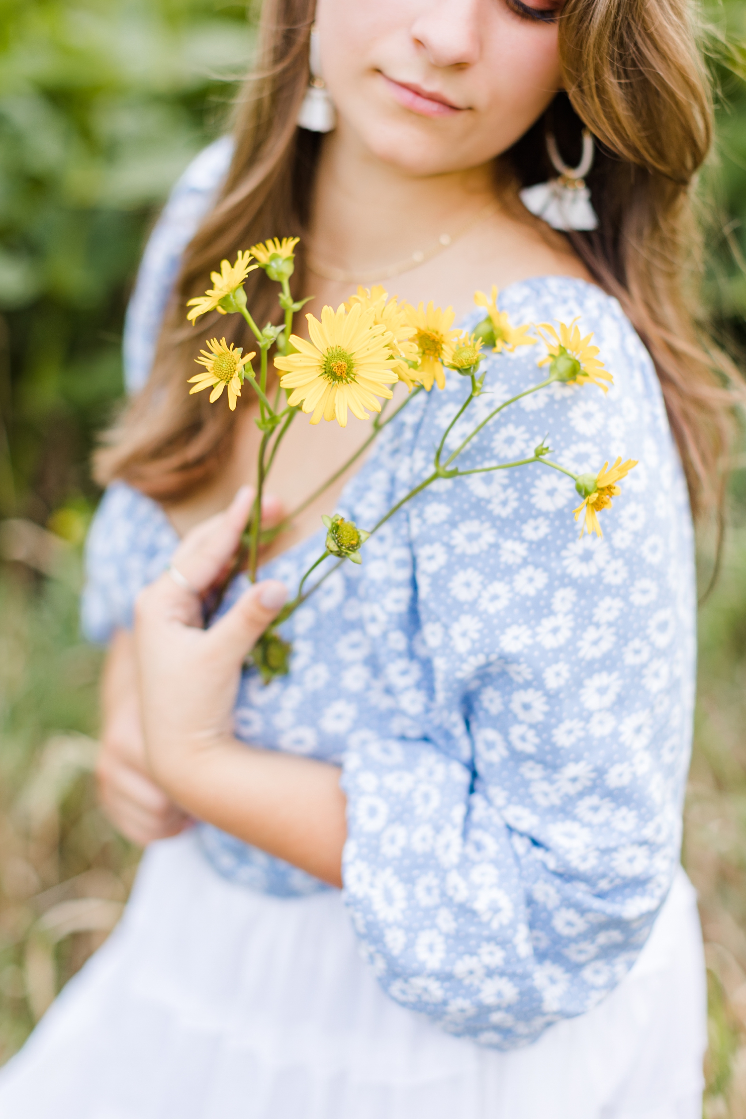Caitlin closes holds flowers to her chest in a field of yellow wildflowers | CB Studio