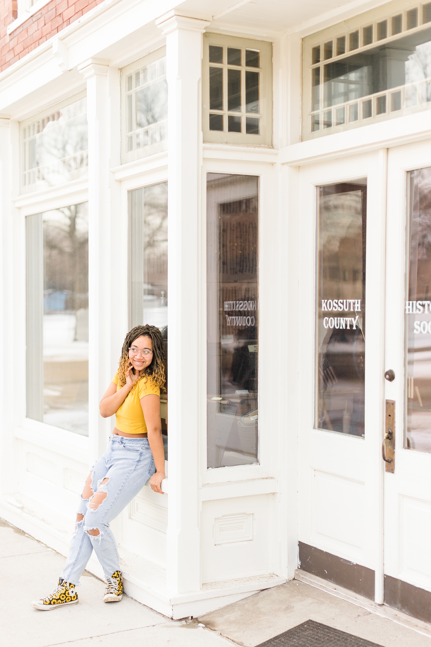 Marie leans against a historical white building in downtown Algona | CB Studio