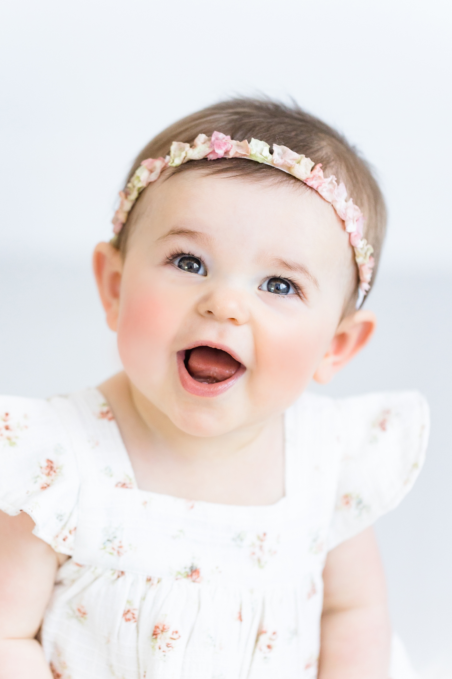 Happy Baby Baker wearing a white floral dress and flower petal headband | CB Studio