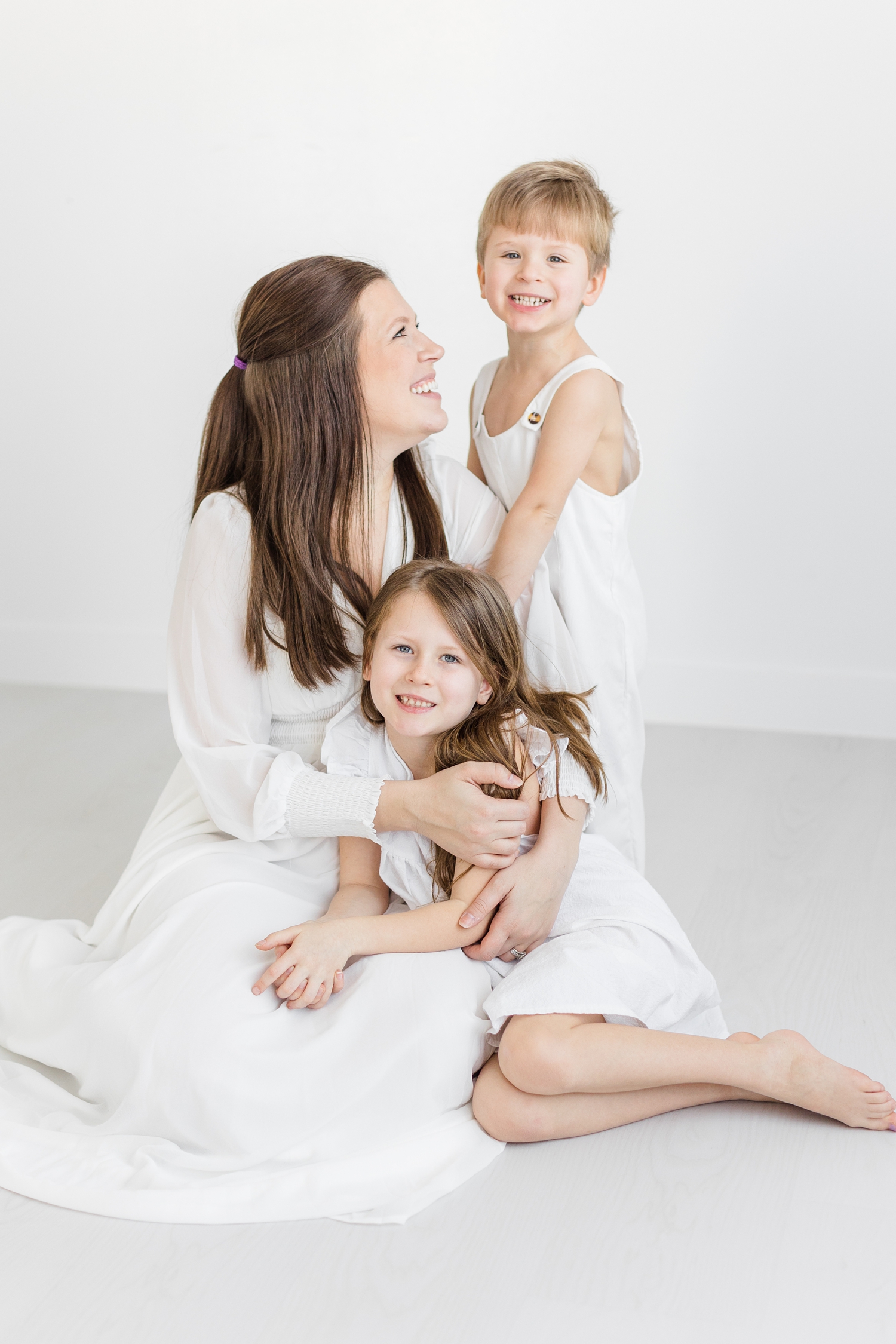 Brandee smile at her two children during a signature white studio photography session | CB Studio