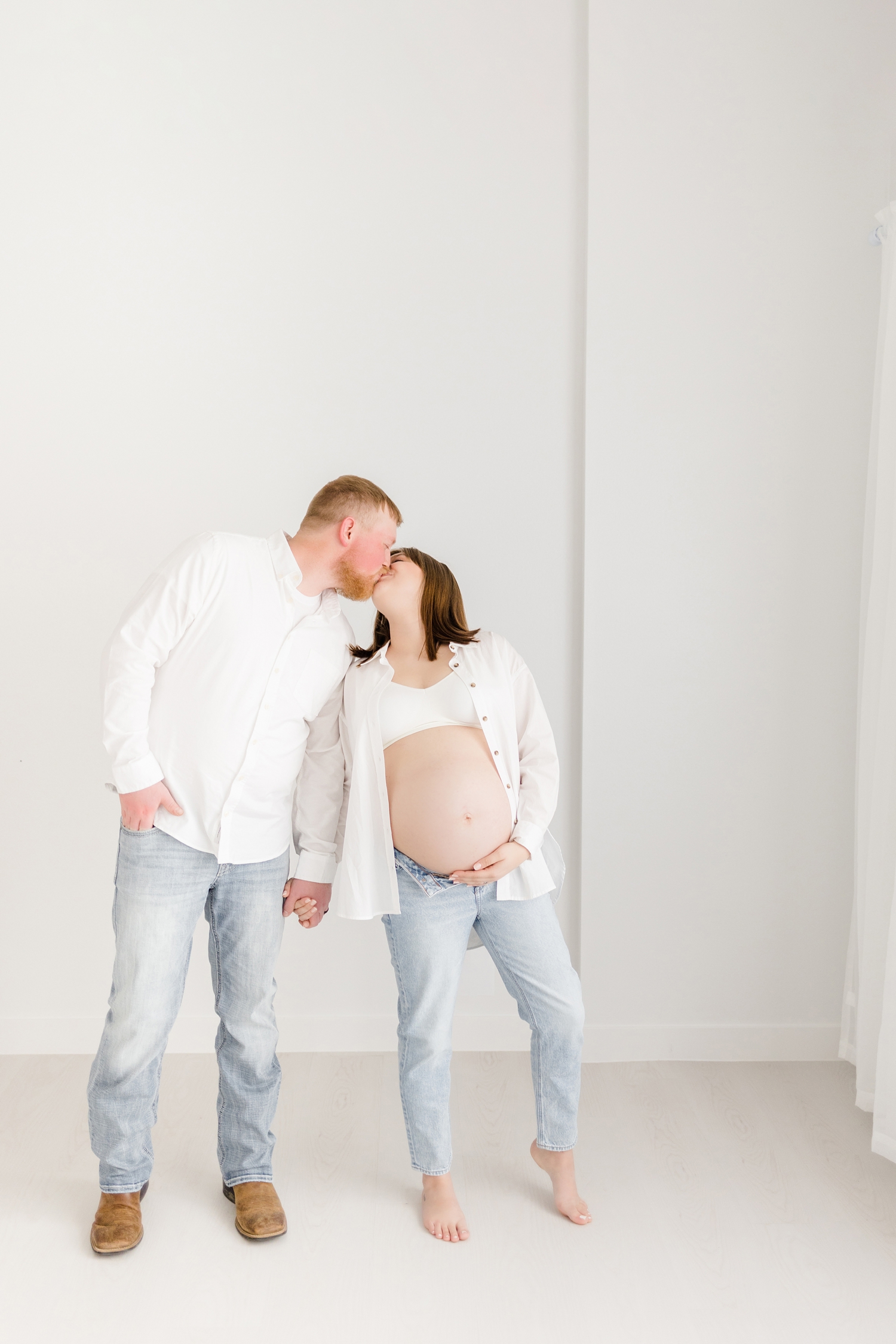 Madeline and Jeremiah lean towards each other to share a kiss while holding Madeline's baby belly | CB Studio Photography