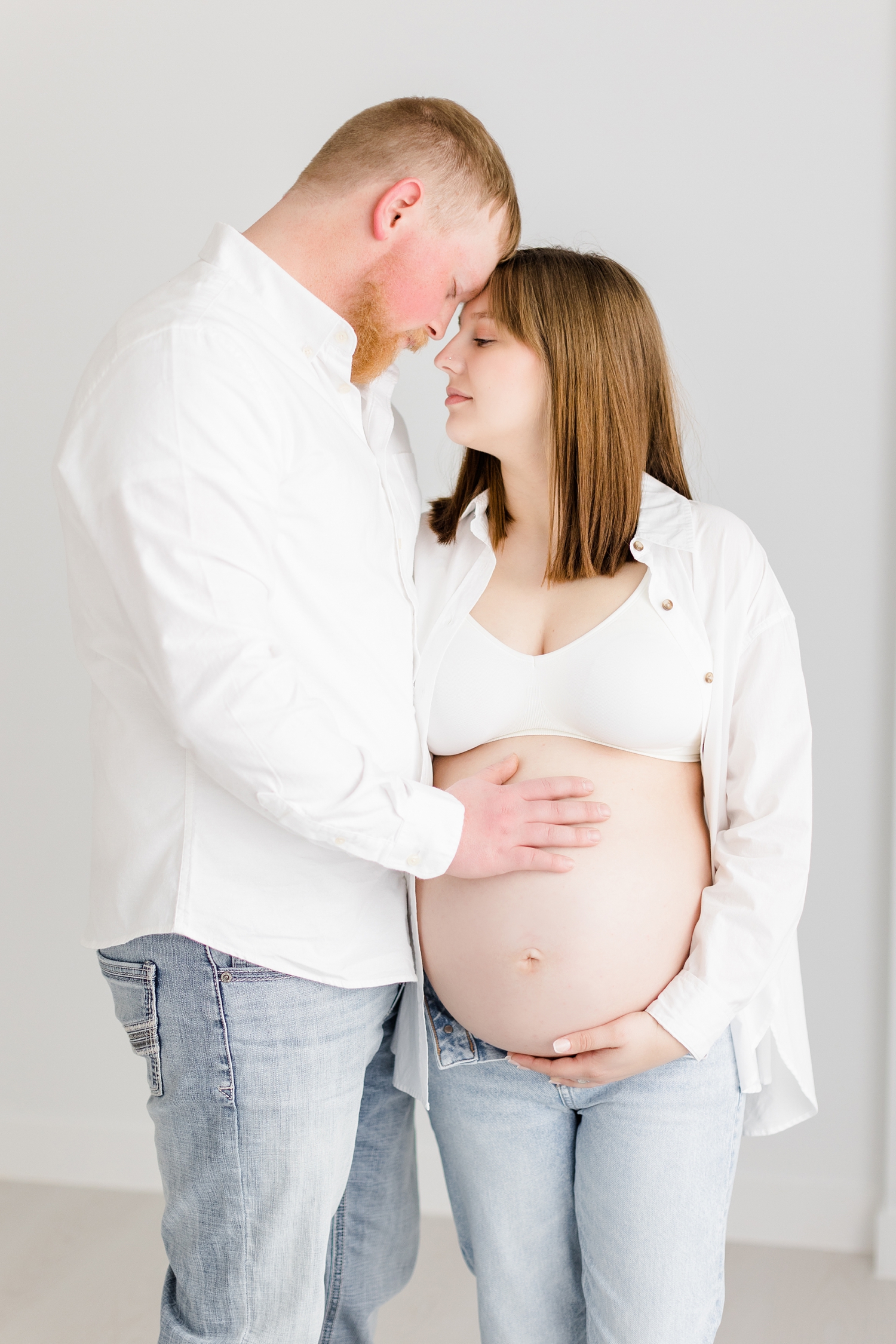 Madeline and Jeremiah rest their foreheads together as they both hold Madeline's baby belly | CB Studio Photography