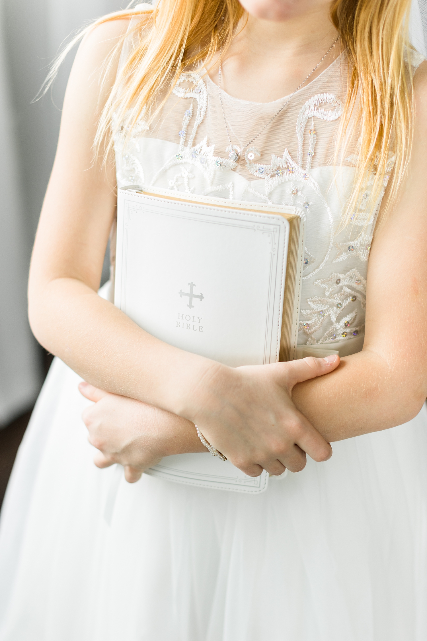 First Communicant holds her brand new white bible close | CB Studio 