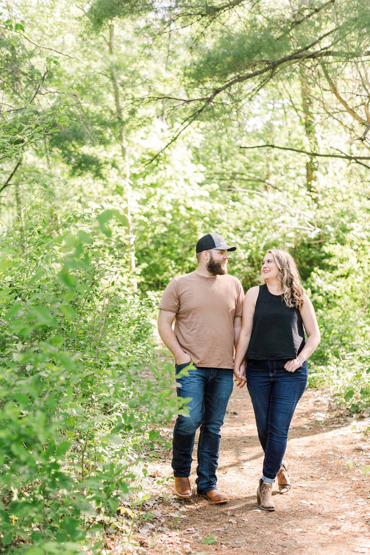 Megan and Matt hold hands and walk along a path at Jester Park in Granger Iowa | CB Studio