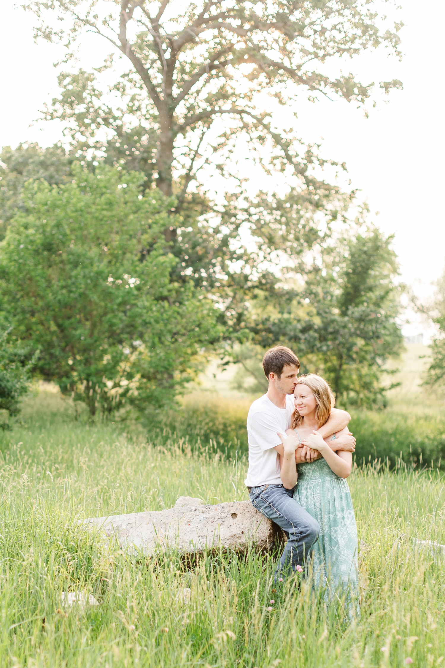 Zane hugs McKennan's tight and gently kisses her head in a grassy field | CB Studio