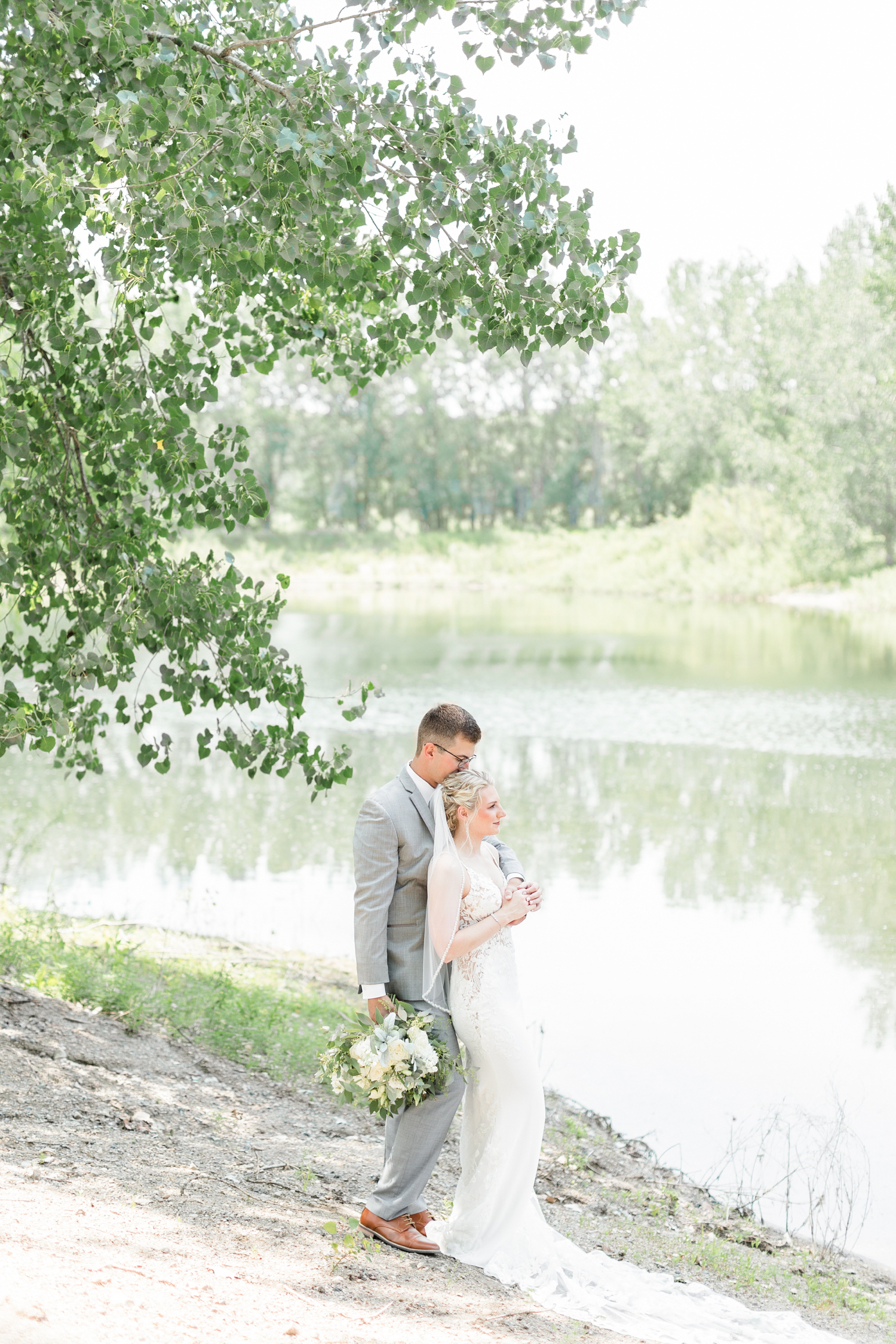 Quinton and Alli hold each other close while looking at the lake at Wild Haven in Algona, IA | CB Studio