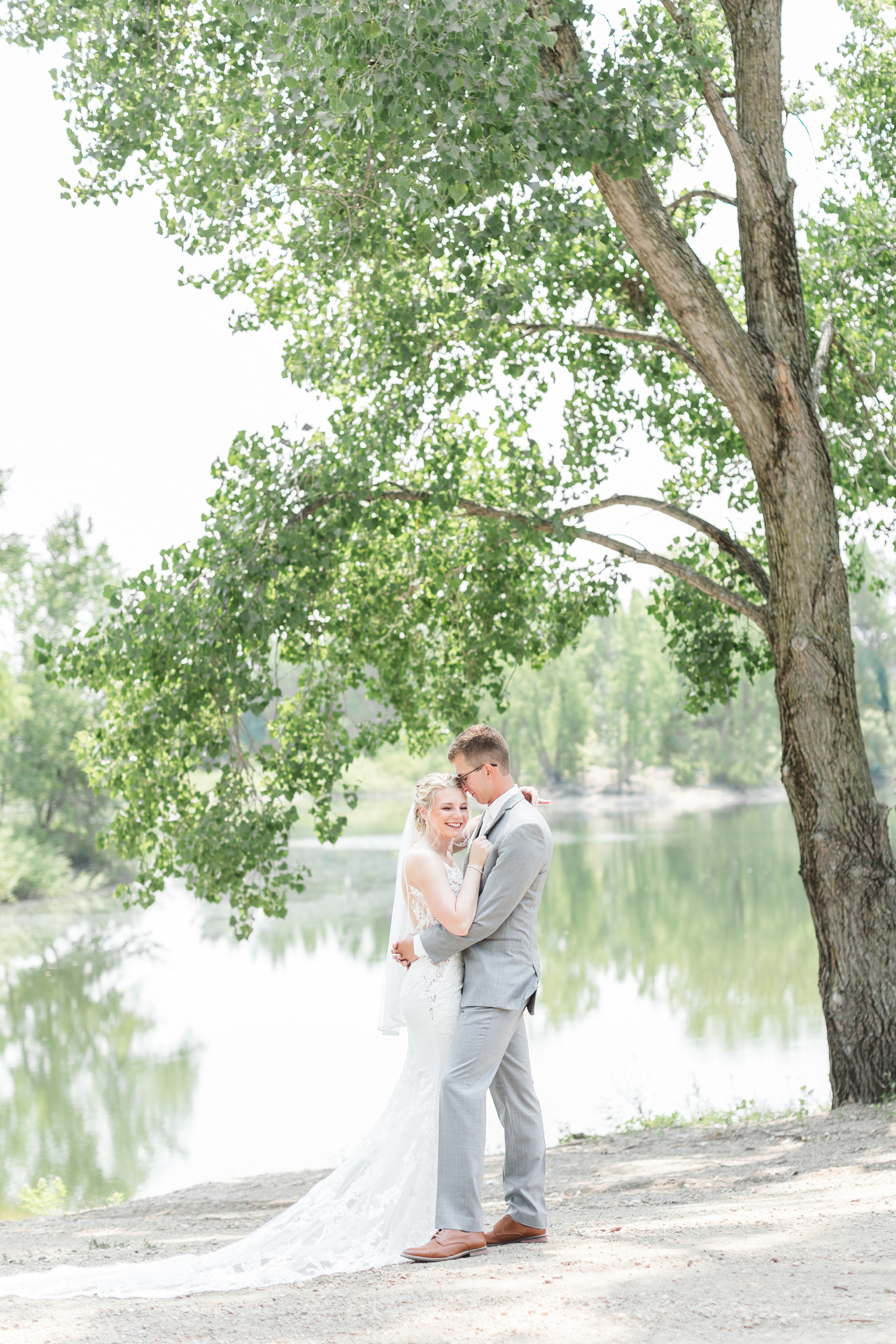 Quinton holds Alli close while he nuzzles her in front of a scenic pond at Wild Haven in Algona, IA | CB Studio
