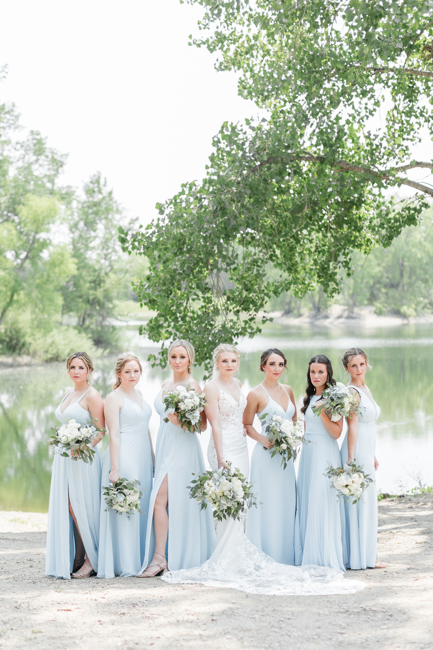 Alli and her bridesmaids, dressed in sky blue, pose in front of a pond at Wild Haven | CB Studio