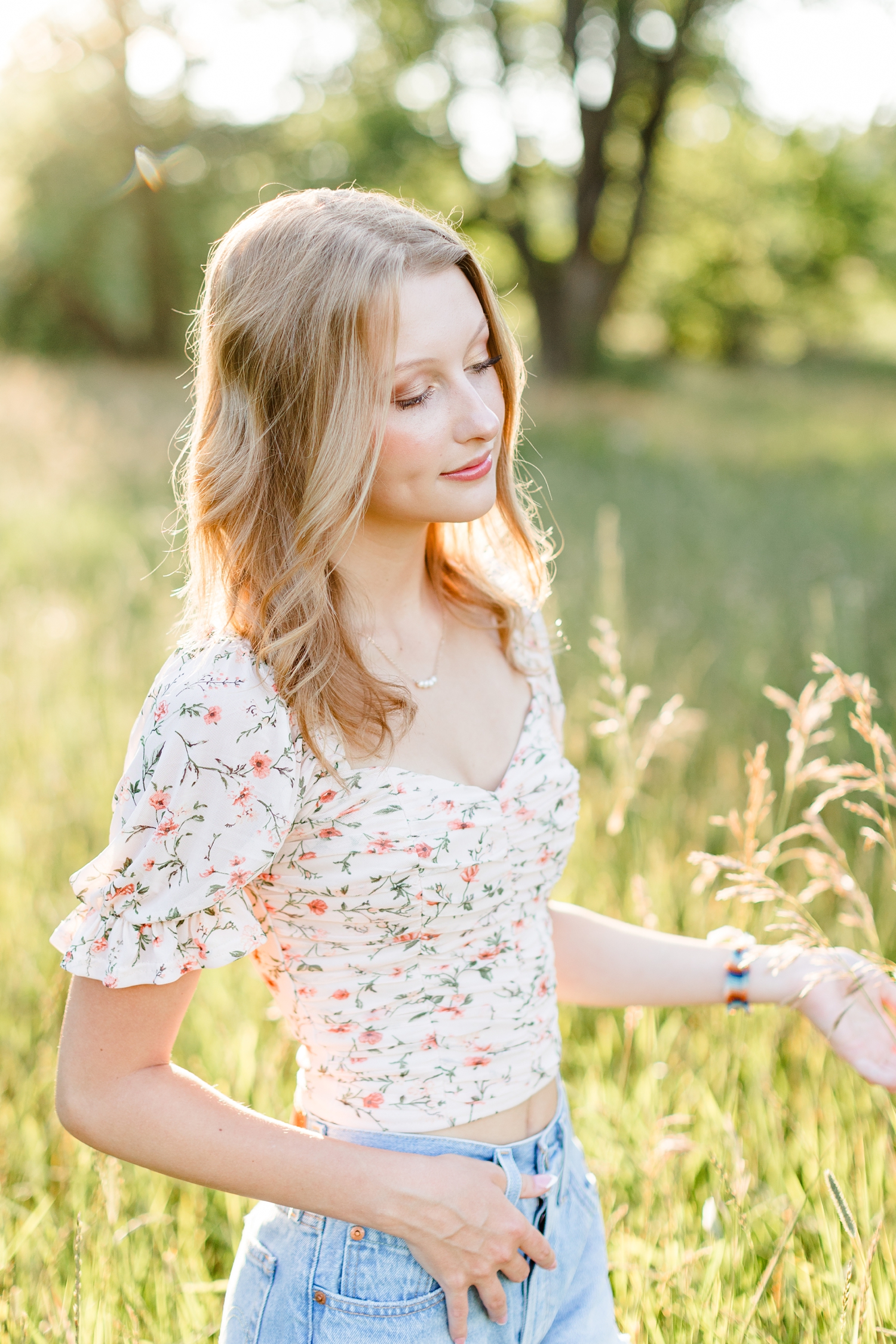 Ryley closes her eyes as she strolls through a grassy pasture at golden hour | CB Studio