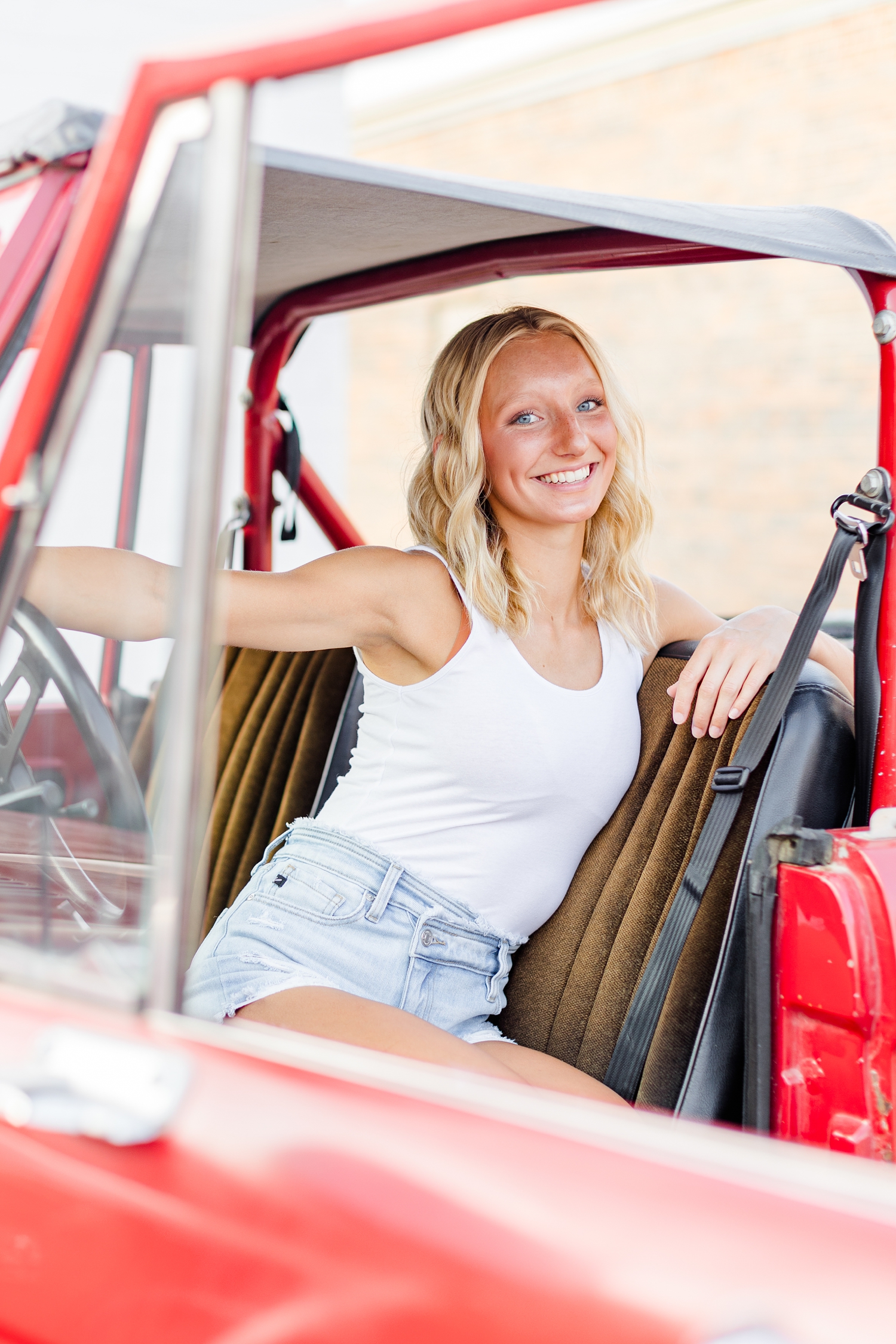 Avery sits in the front seat of a 1974 red Bronco in downtown Algona, IA | CB Studio