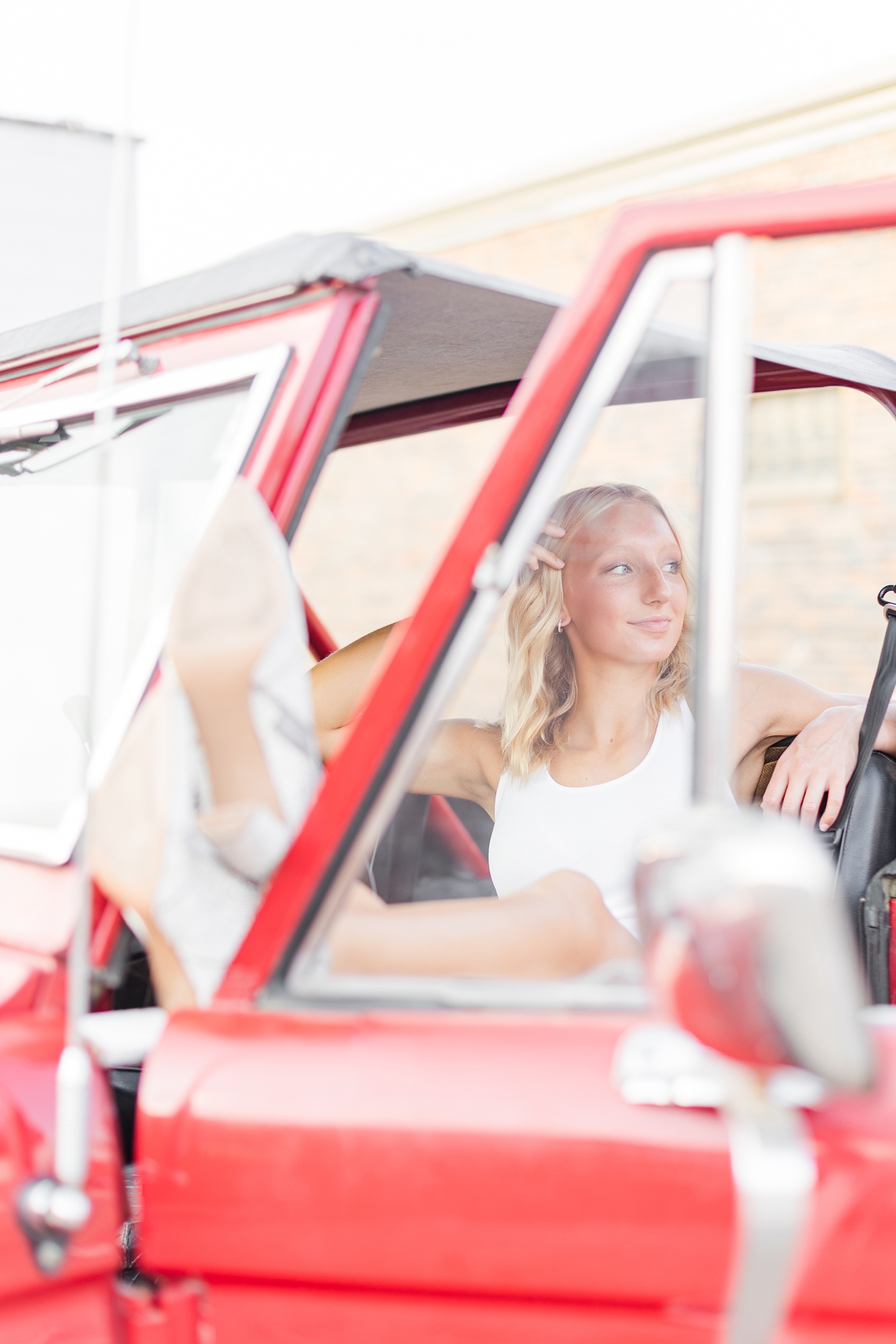 Avery kicks her feet up in the front seat of a 1974 red Bronco in downtown Algona, IA | CB Studio