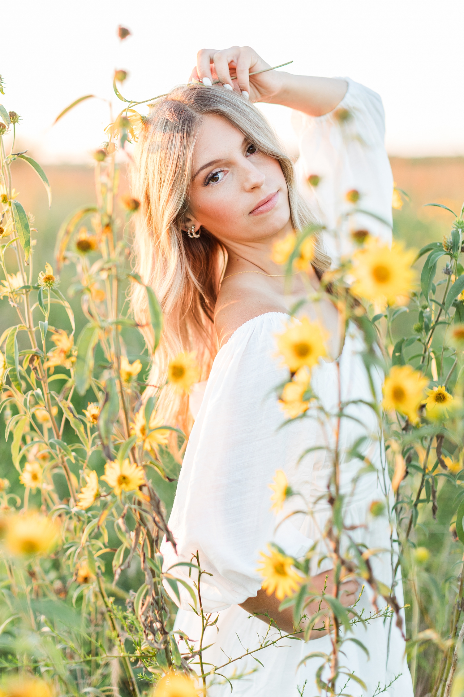 Eden stands in a wildflower field at golden hour wearing a white dress | CB Studio