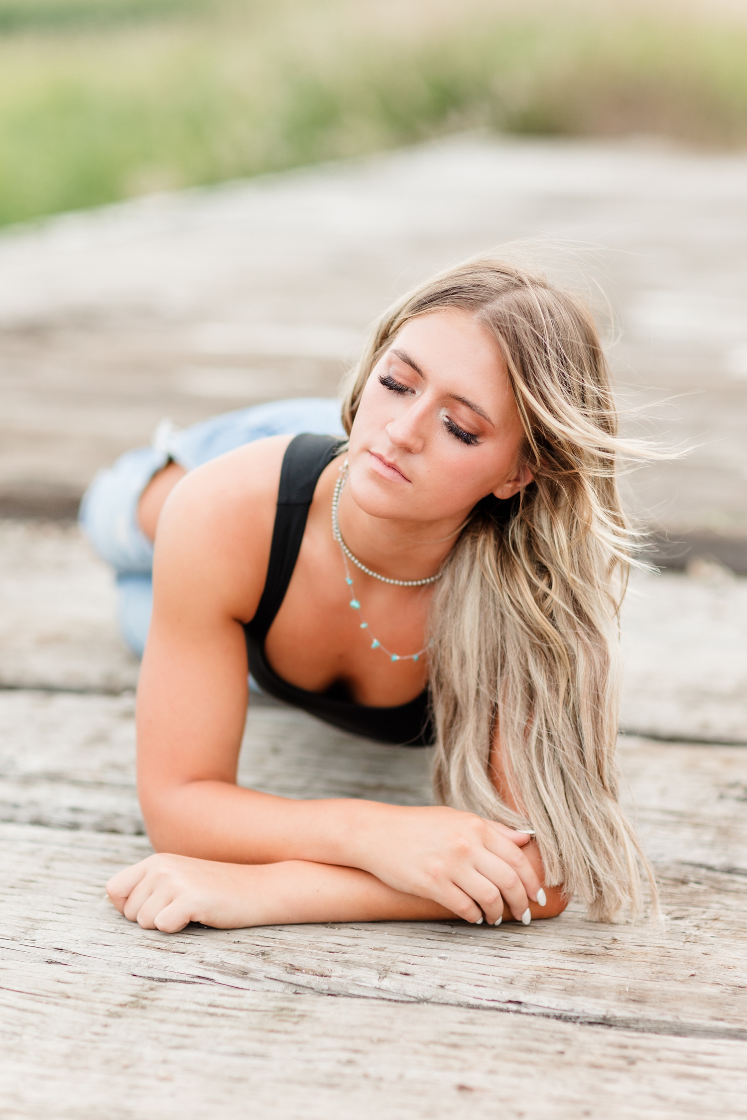 Jenna lays on an old wooden bridge as she closes her eyes and lets the wind blow through her hair | CB Studio