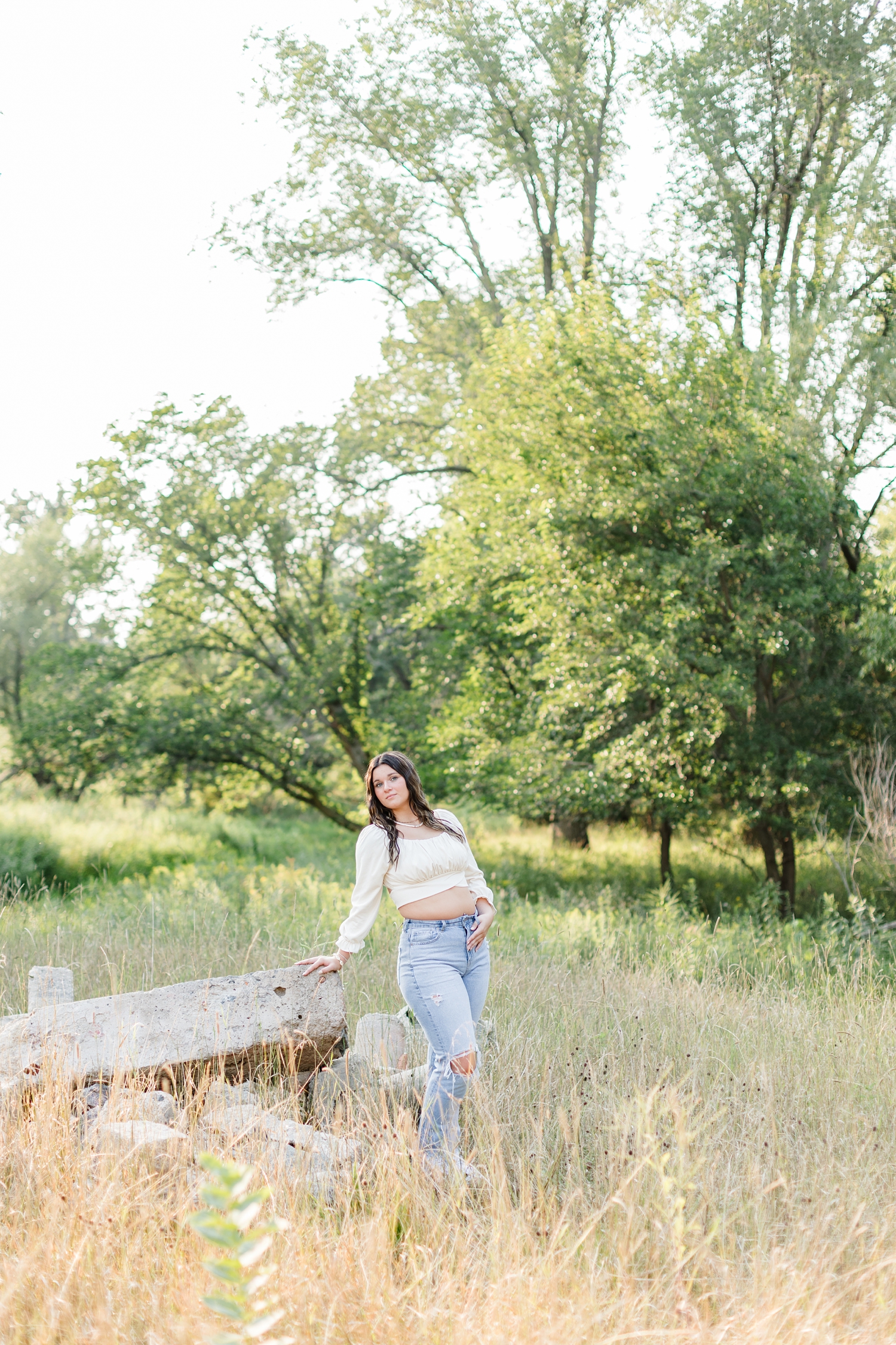 Lily leans against large stones in the middle of a grassy field | CB Studio